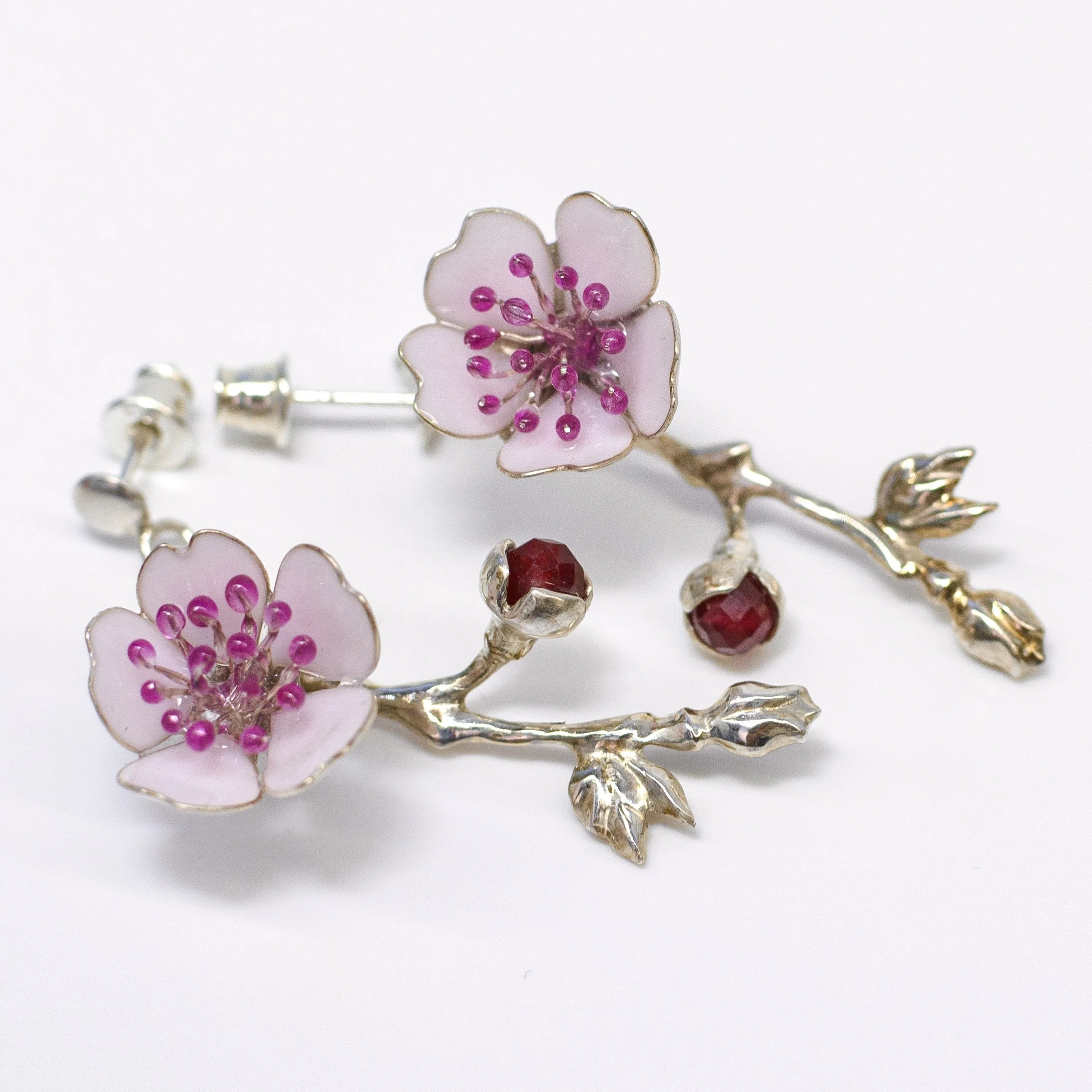 Close-up of a pink flower brooch with a silver stem and pink bead accents, set against a white background.