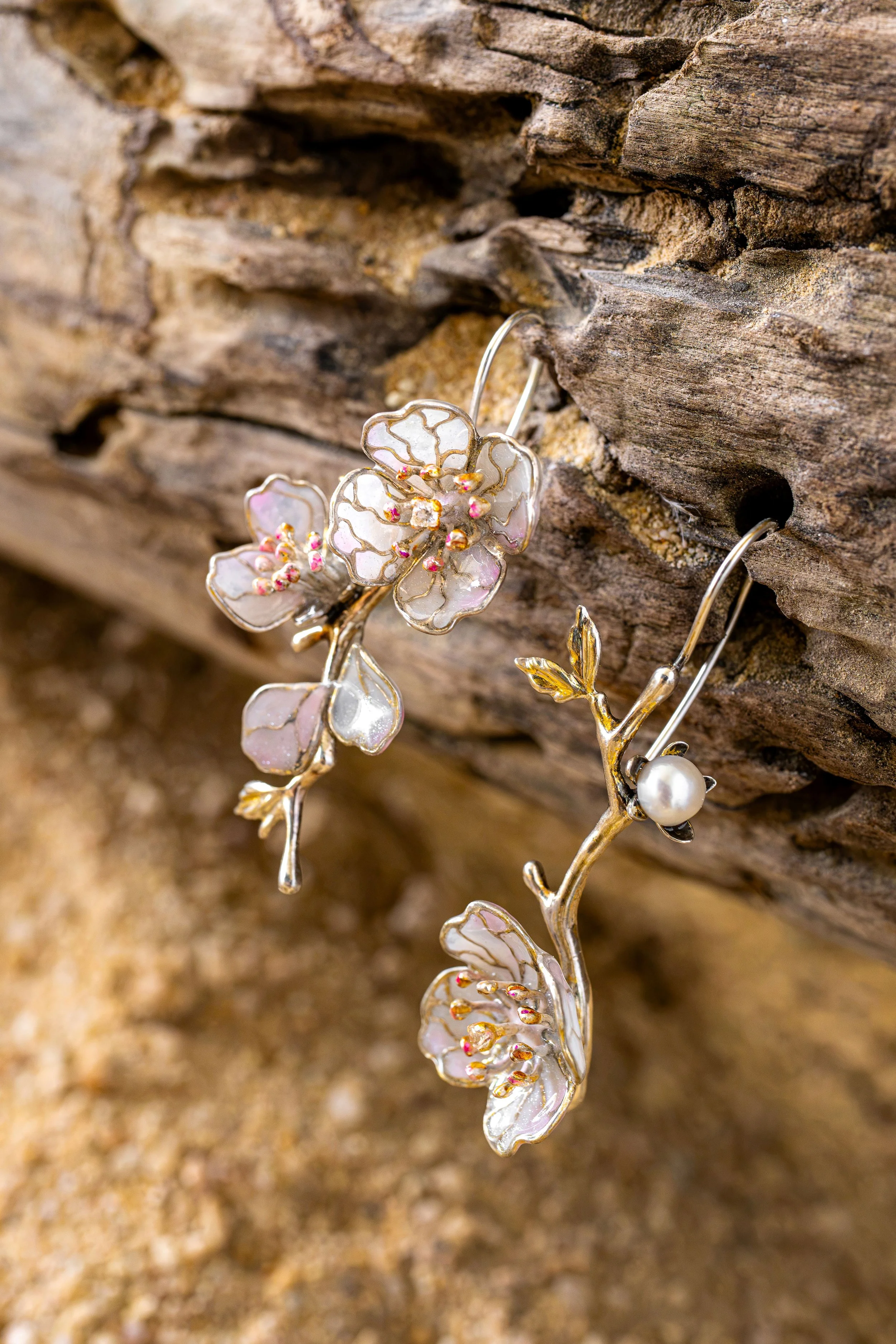 Close-up of a decorative flower-shaped jewelry piece with pink and white details, hanging on a textured wooden surface.