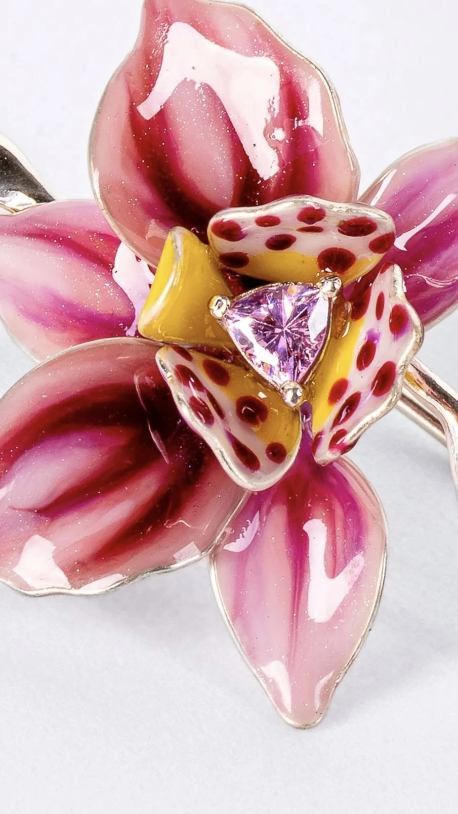 A decorative glass flower with pink, yellow, and red elements, including a pink gemstone at the center.