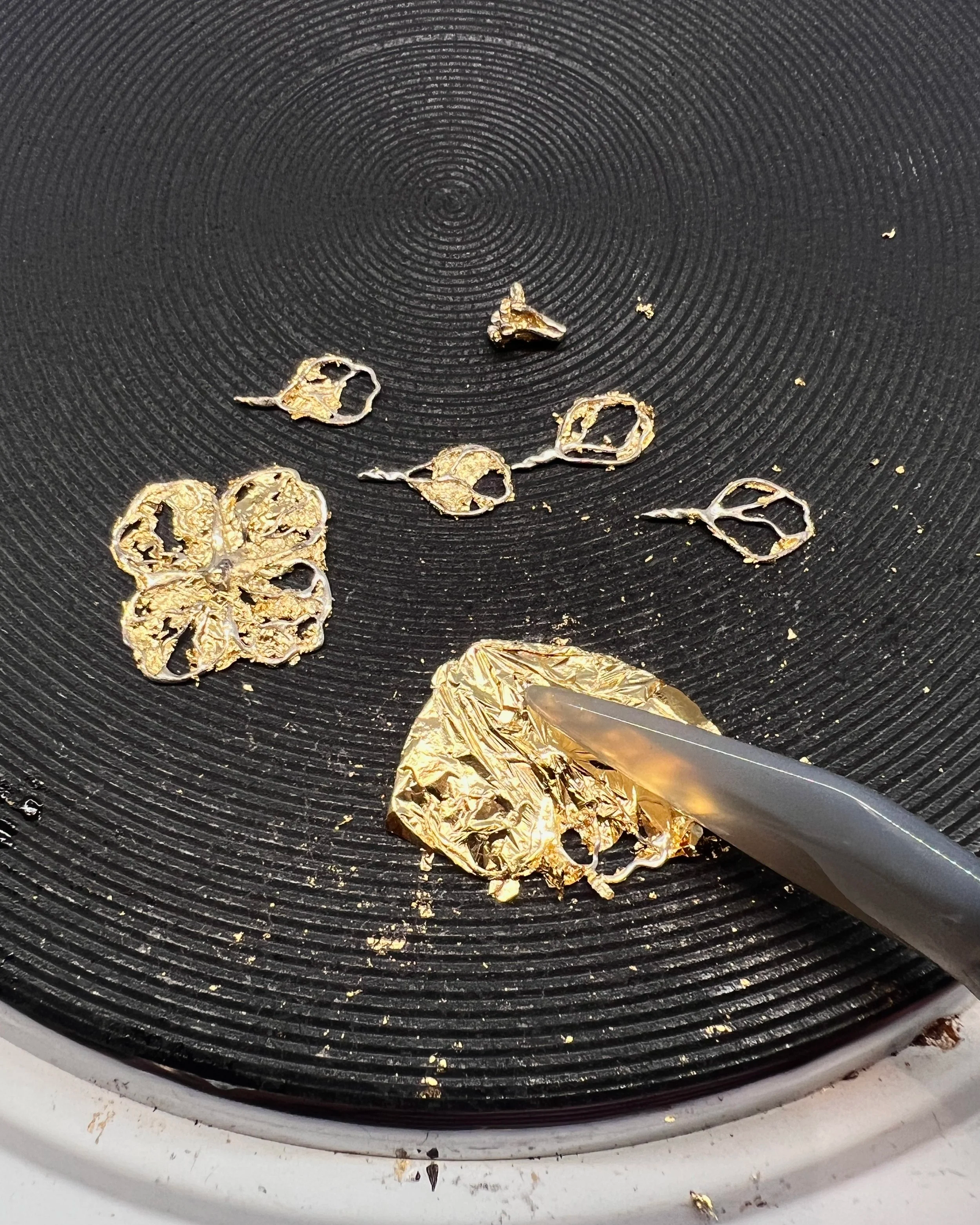 Burnt gold foil and orange peel on a black stovetop burner.