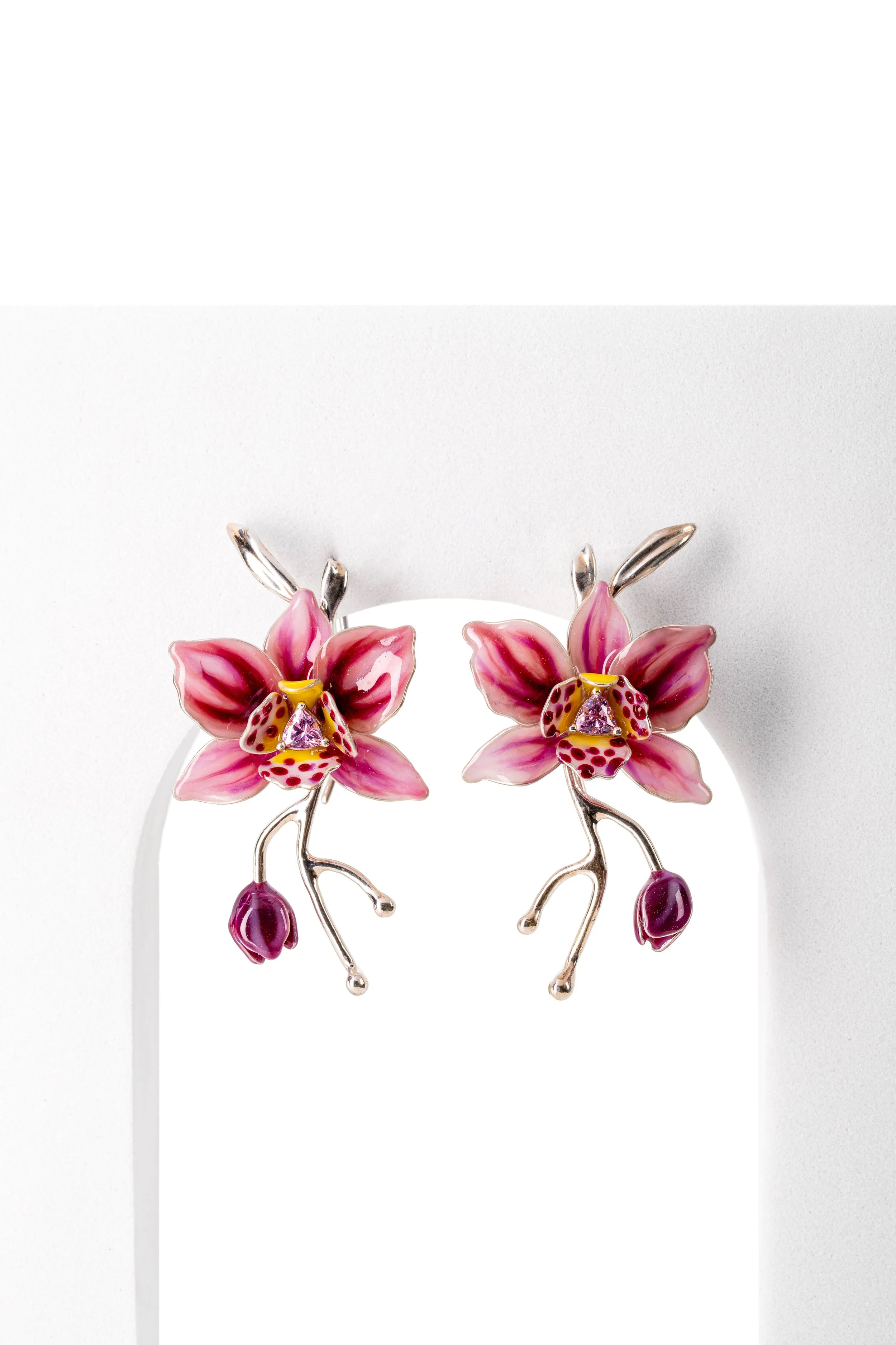 Pink and purple floral earrings with silver branches and pink gemstone accents displayed on a white background.