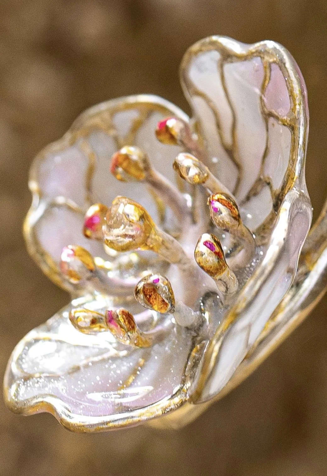 Close-up of a decorative glass flower with golden accents and pink details.