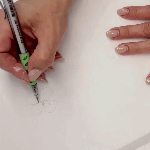 Person drawing a flower on paper with a pen.