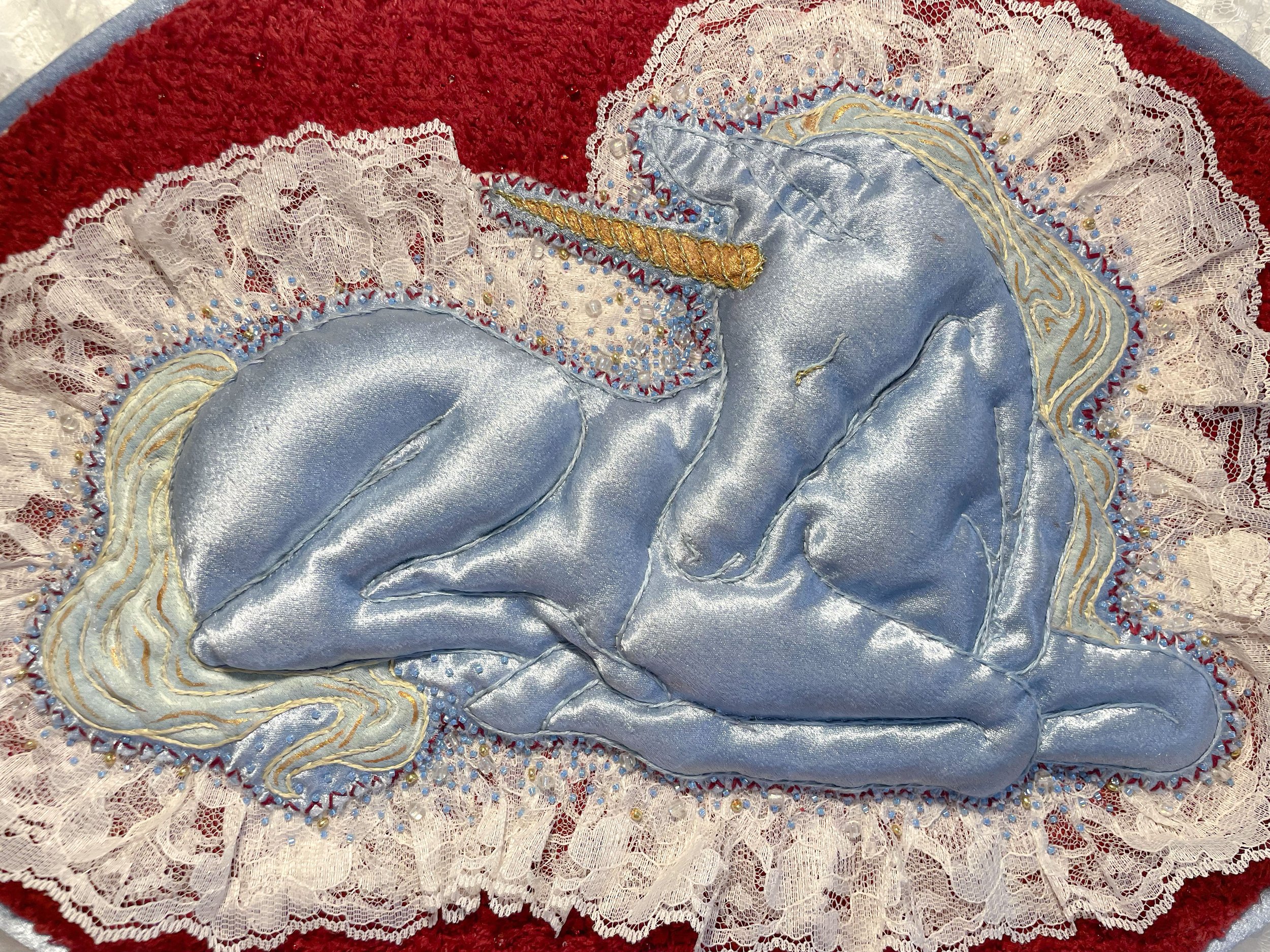"Blue Unicorn," (2026). Satin, lace, canvas, plush fabric, embroidery floss, metallic thread, beads, Polyfil. 