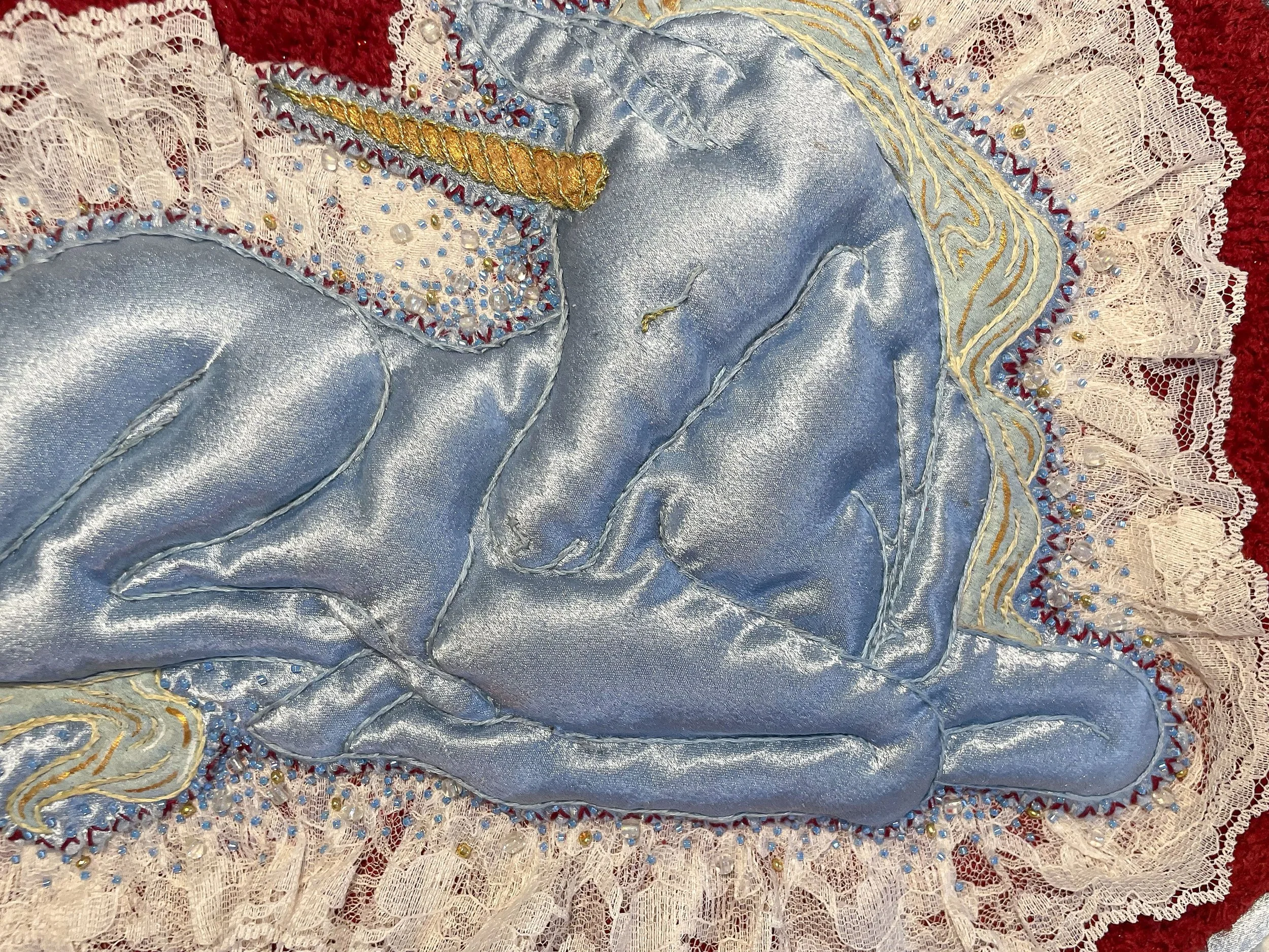 "Blue Unicorn," (2026). Satin, lace, canvas, plush fabric, embroidery floss, metallic thread, beads, Polyfil. 