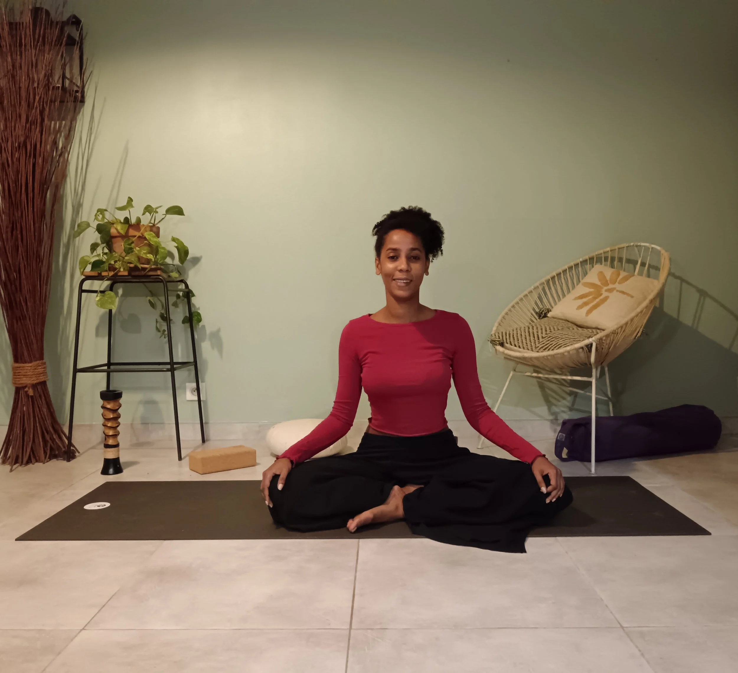 Warda assise sur un tapis dans son espace de yoga à Nice