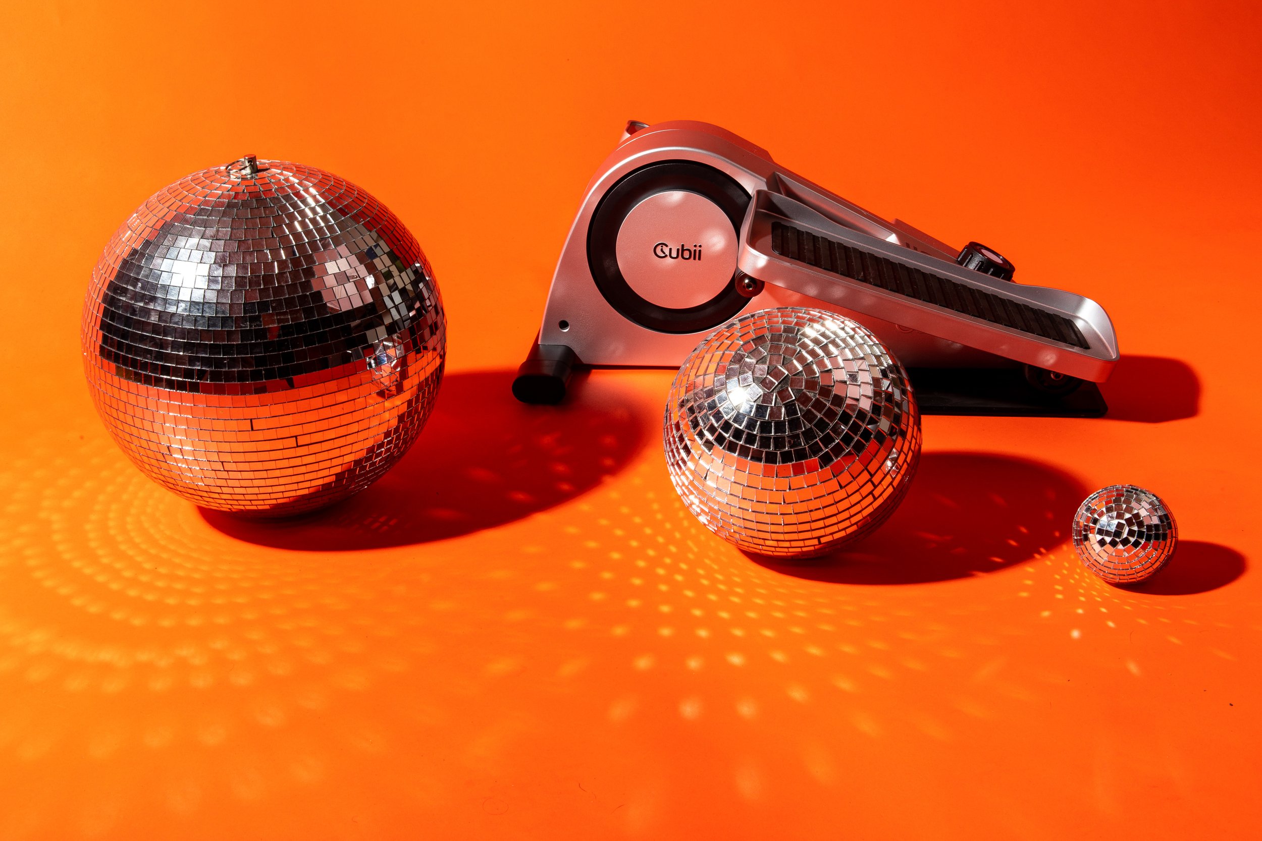 Disco balls of various sizes reflecting light on an orange background with a stereo turntable labeled 'Cubii'.