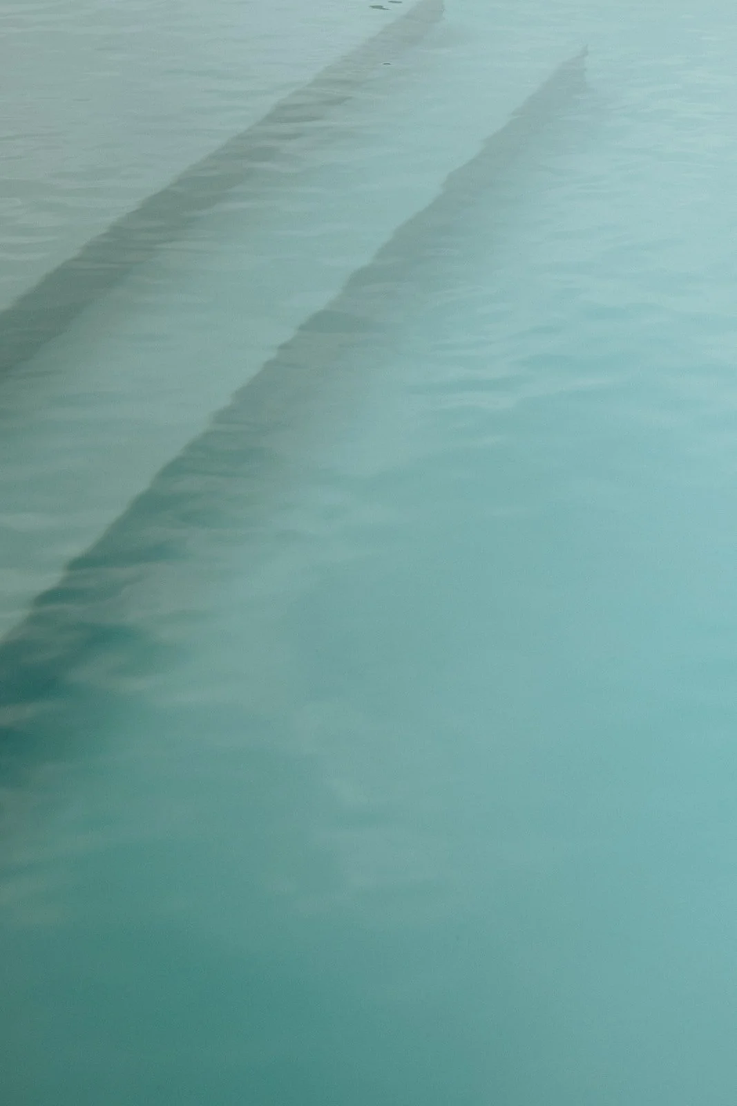 Close-up of a stairway underwater, with visible steps casting shadows on the ocean floor.