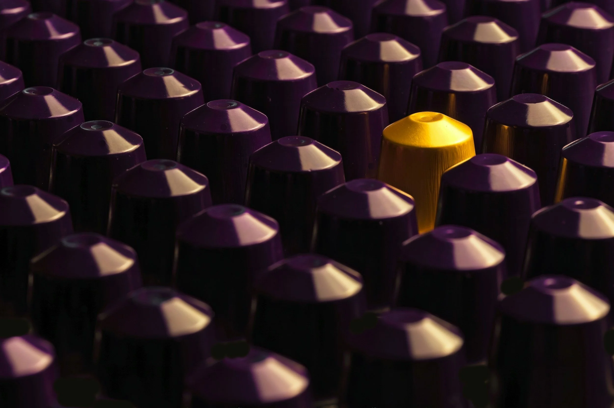Close-up of numerous purple capsules with one gold capsule among them.