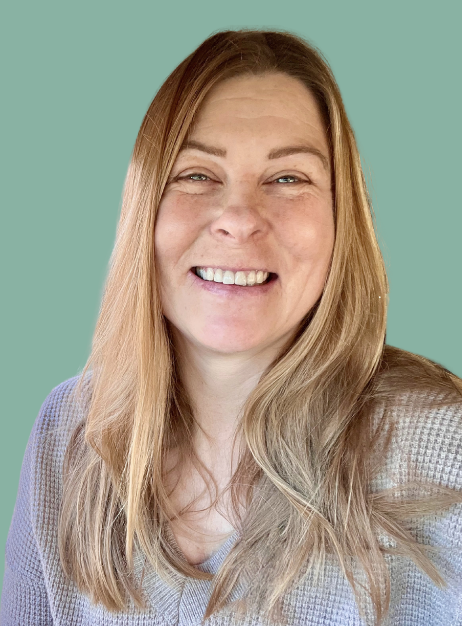 A woman with long, light brown hair smiling at the camera with a green background.