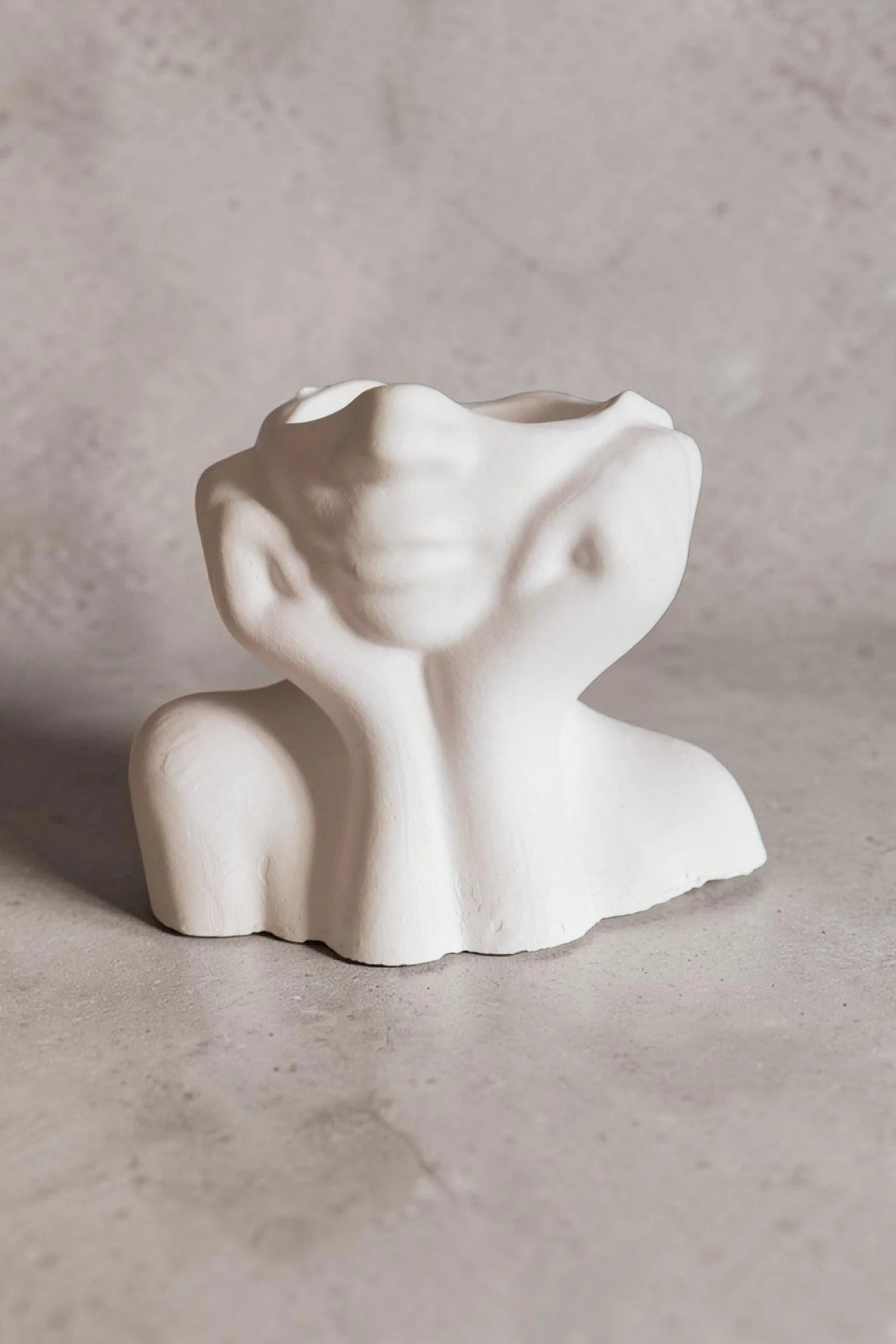 White sculpture makeup brush holder, minimalistic and smooth in texture, set against a plain, light-colored background.
