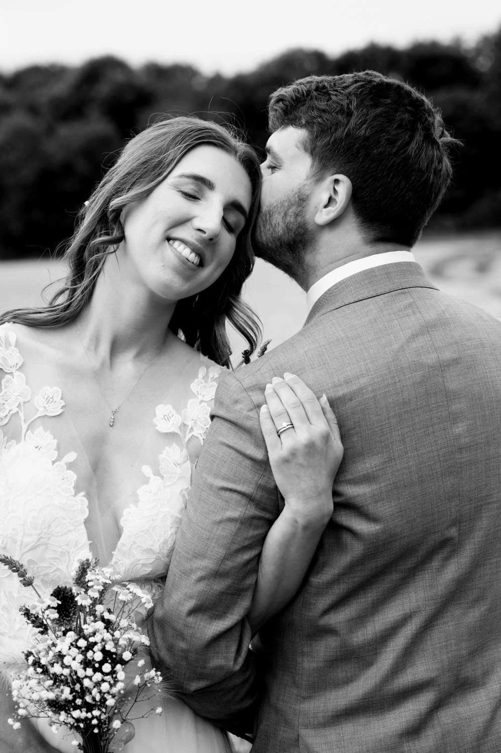 Groom kissing his bride on the cheek as she smiles with pure happiness at The Courtyard Barns, Leicestershire — romantic candid wedding portrait by Tasha Boorman, Leicestershire wedding photographer