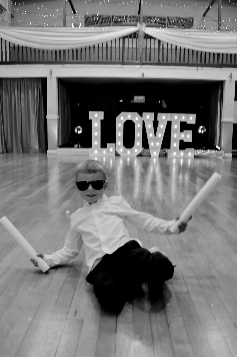 Young wedding guest totally owning the dancefloor in sunglasses in front of illuminated LOVE letters — candid fun wedding photography by Tasha Boorman, Nottinghamshire wedding photographer