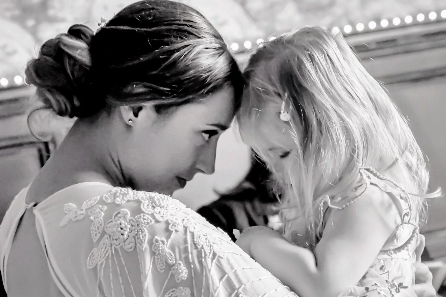 Bride sharing a tender moment with young flower girl, black and white candid wedding portrait, emotional documentary wedding photography