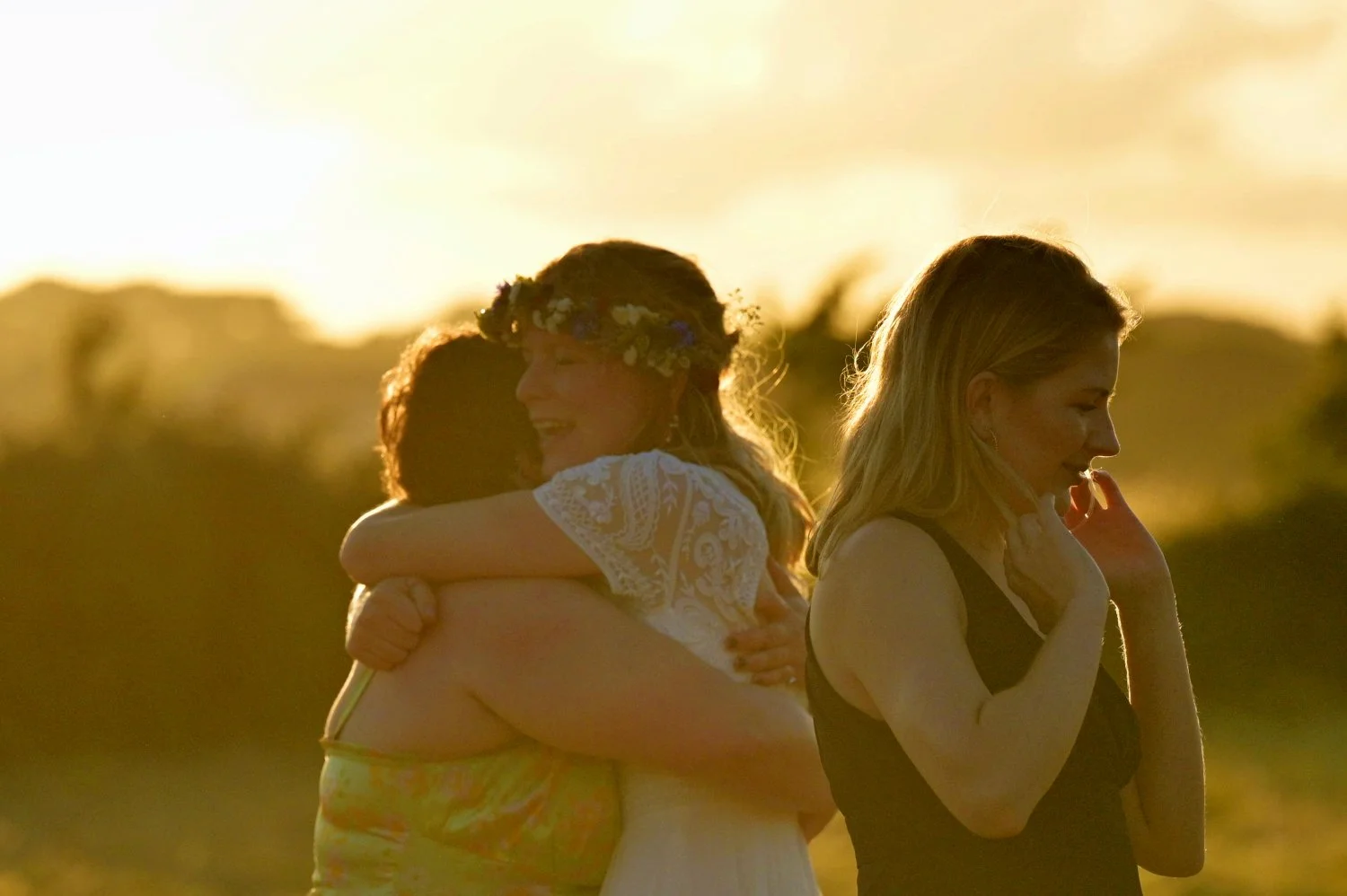 Tender golden hour embrace between bride and friend at a festival style wedding — candid documentary wedding photography by Tasha Boorman, Nottinghamshire wedding photographer