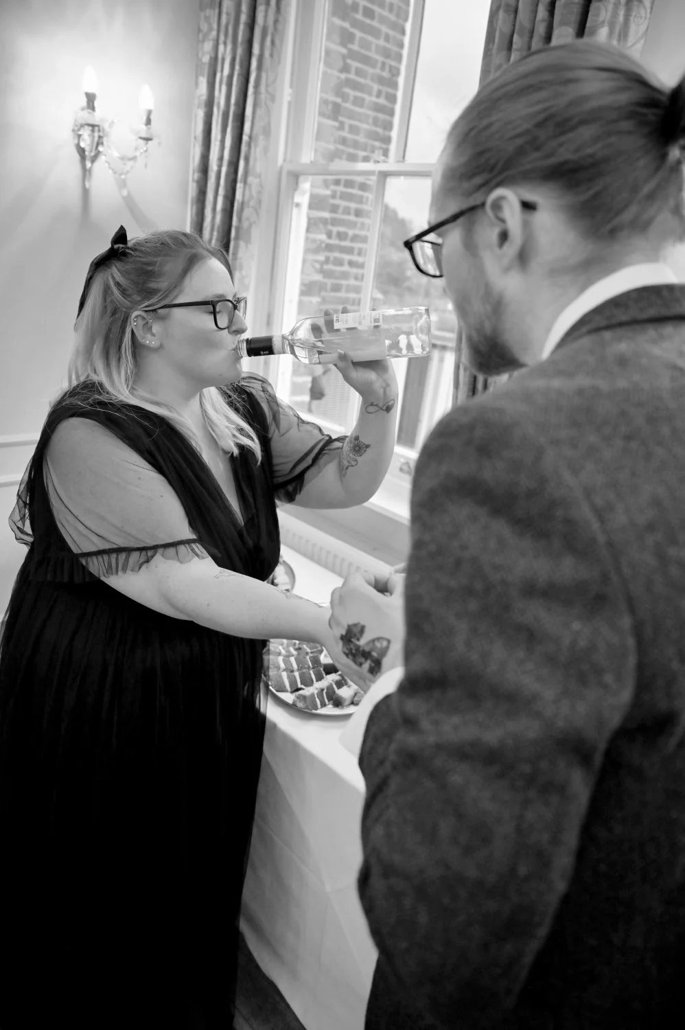 Candid wedding guest moment — bridesmaid drinking straight from the bottle during the wedding reception — fun documentary wedding photography by Tasha Boorman, Nottinghamshire wedding photographer