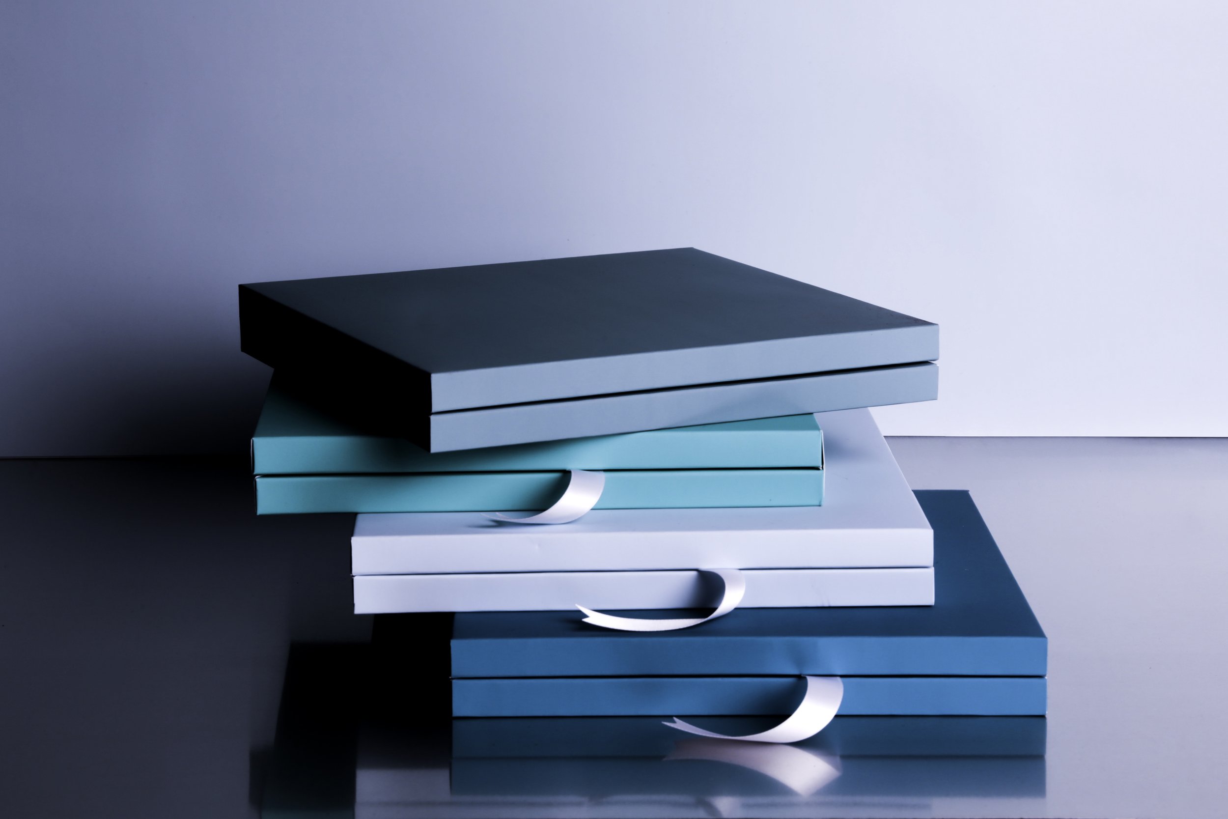 Stacked blue and white books or boxes with white ribbons against a light background.