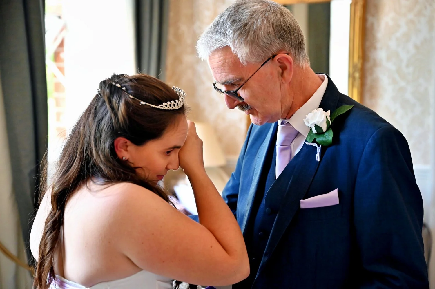 Emotional father and bride moment during wedding morning preparations — bride wiping tears during an intimate father daughter moment — candid documentary wedding photography by Tasha Boorman, Nottinghamshire wedding photographer