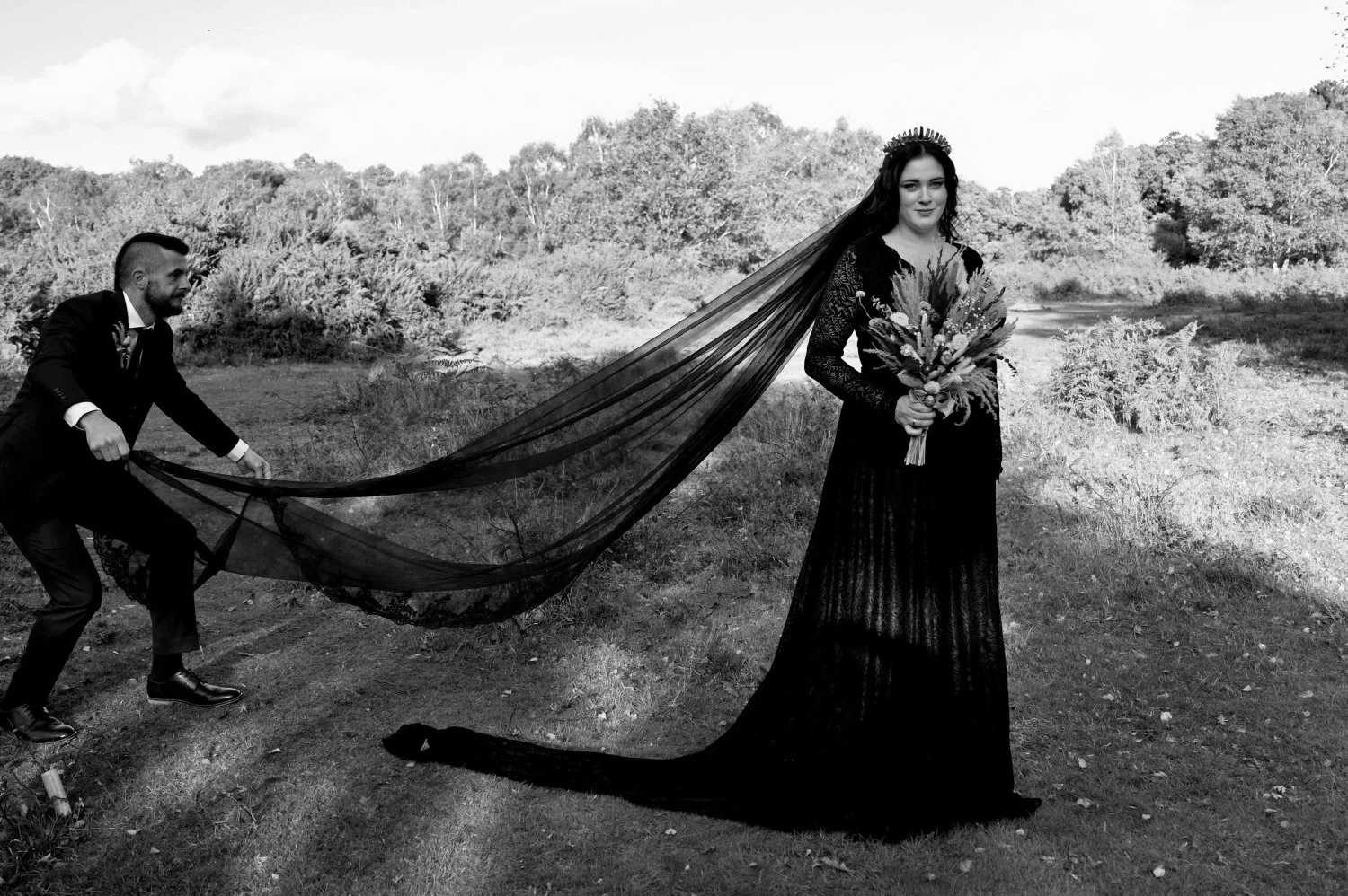 Groom dramatically spreading his gothic bride's stunning black veil across Nottinghamshire heathland — alternative wedding photography by Tasha Boorman, Nottinghamshire wedding photographer