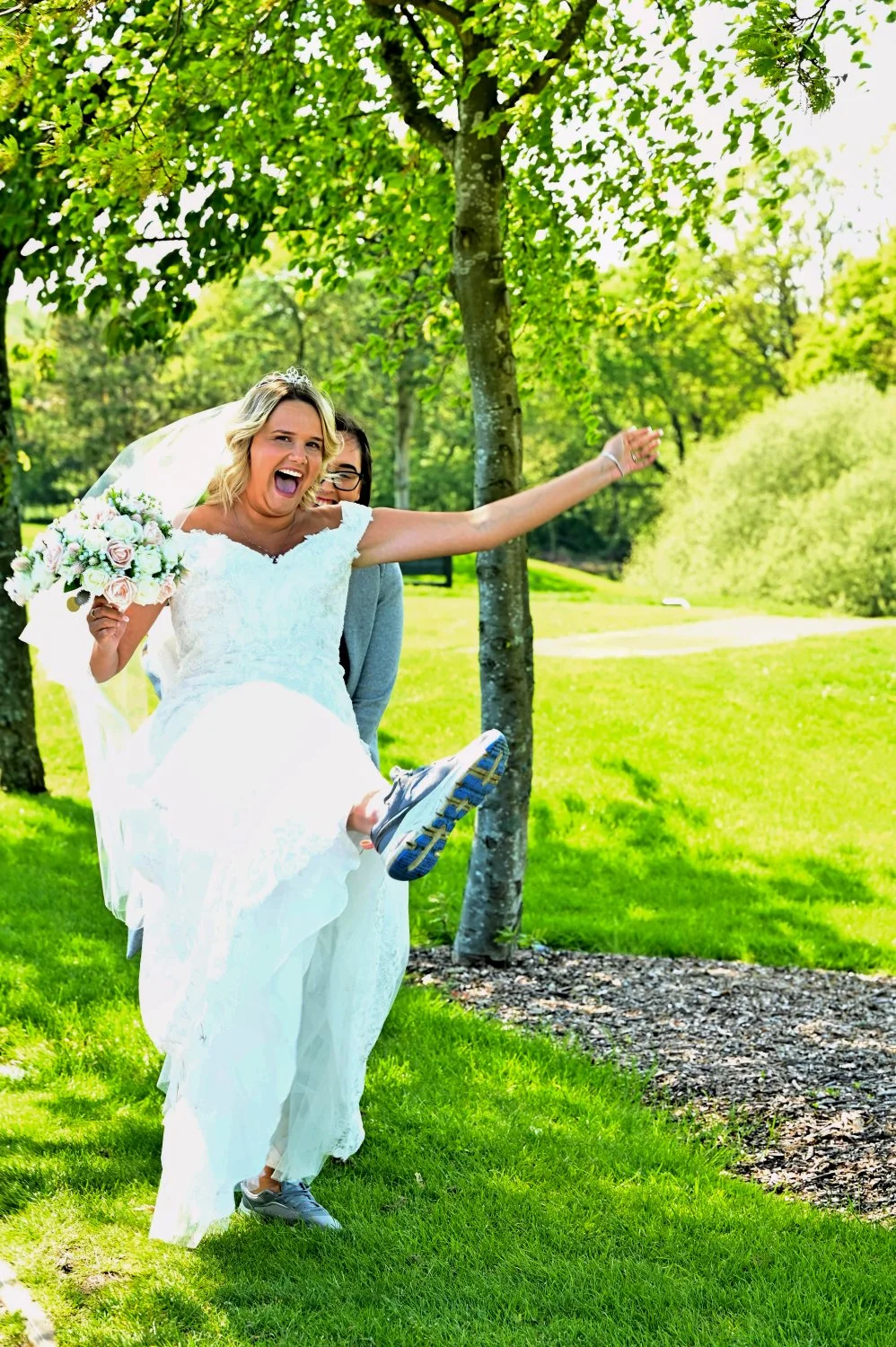 Bride showing off her comfy trainers under her wedding dress with pure joy and laughter — fun candid wedding portrait by Tasha Boorman, Nottinghamshire wedding photographer