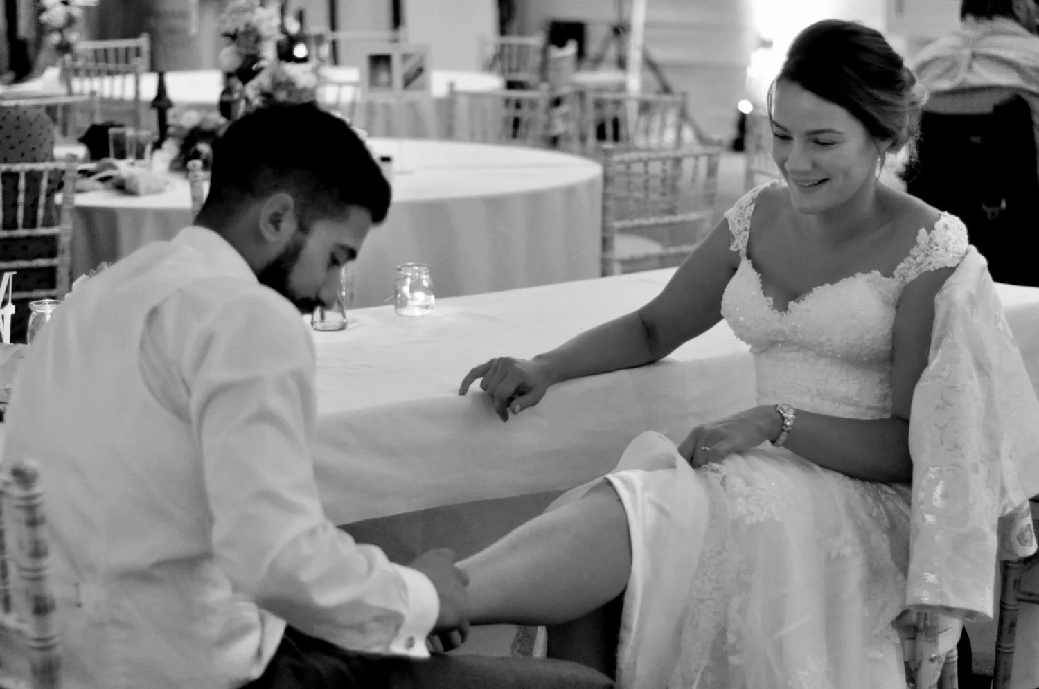 Groom tenderly removing his bride's shoes at the end of their wedding evening — intimate candid moment captured by Tasha Boorman, Nottinghamshire documentary wedding photographer