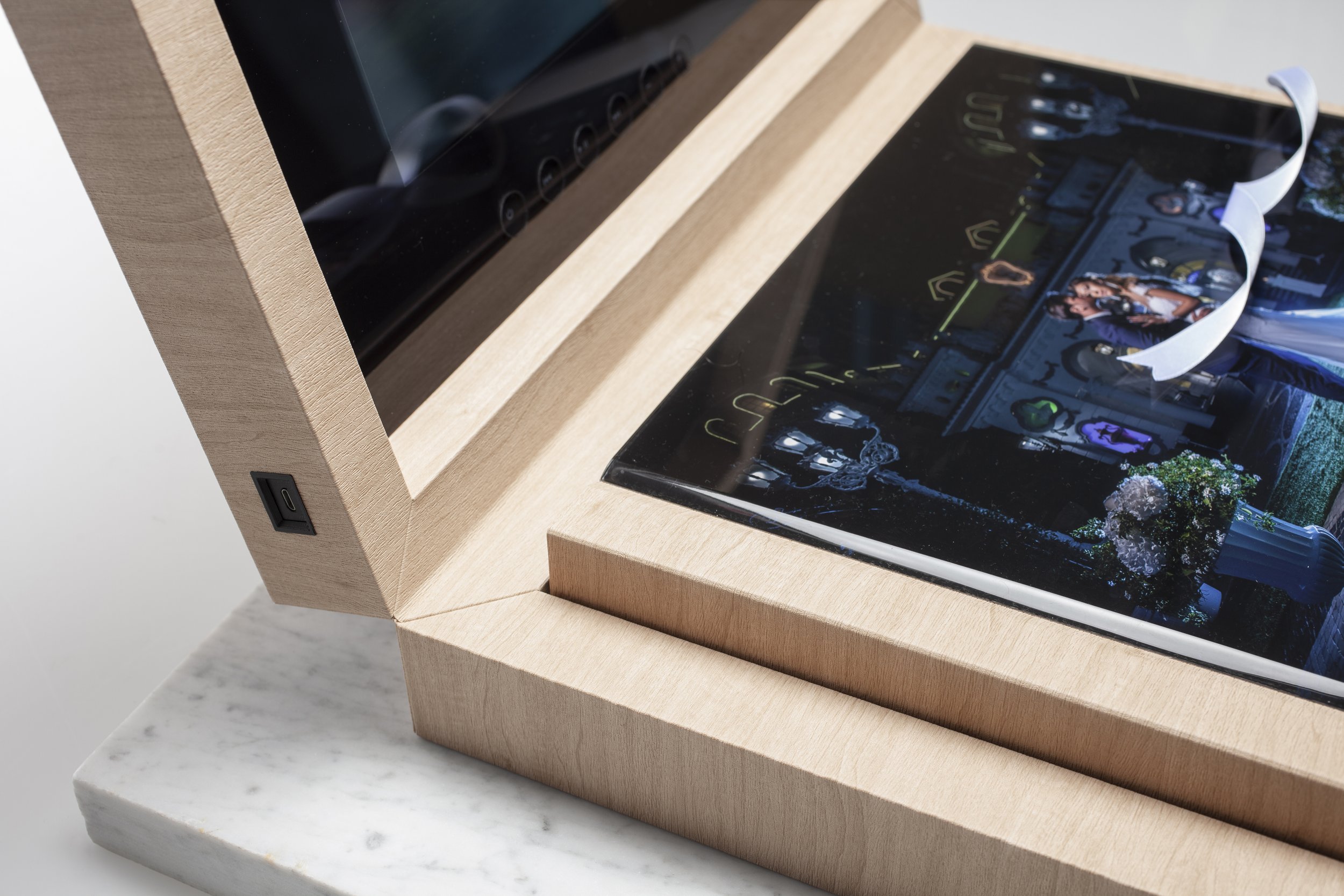 Close-up of a tablet on a wooden stand, displaying a colorful digital image, placed on a light-colored marble surface.