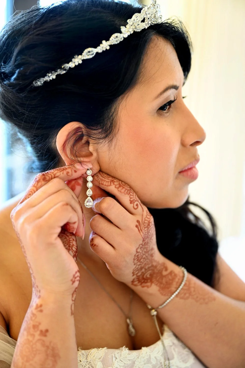 Bride putting on earrings with beautiful henna hands during getting ready at a multicultural wedding — detail wedding photography by Tasha Boorman, Nottinghamshire wedding photographer