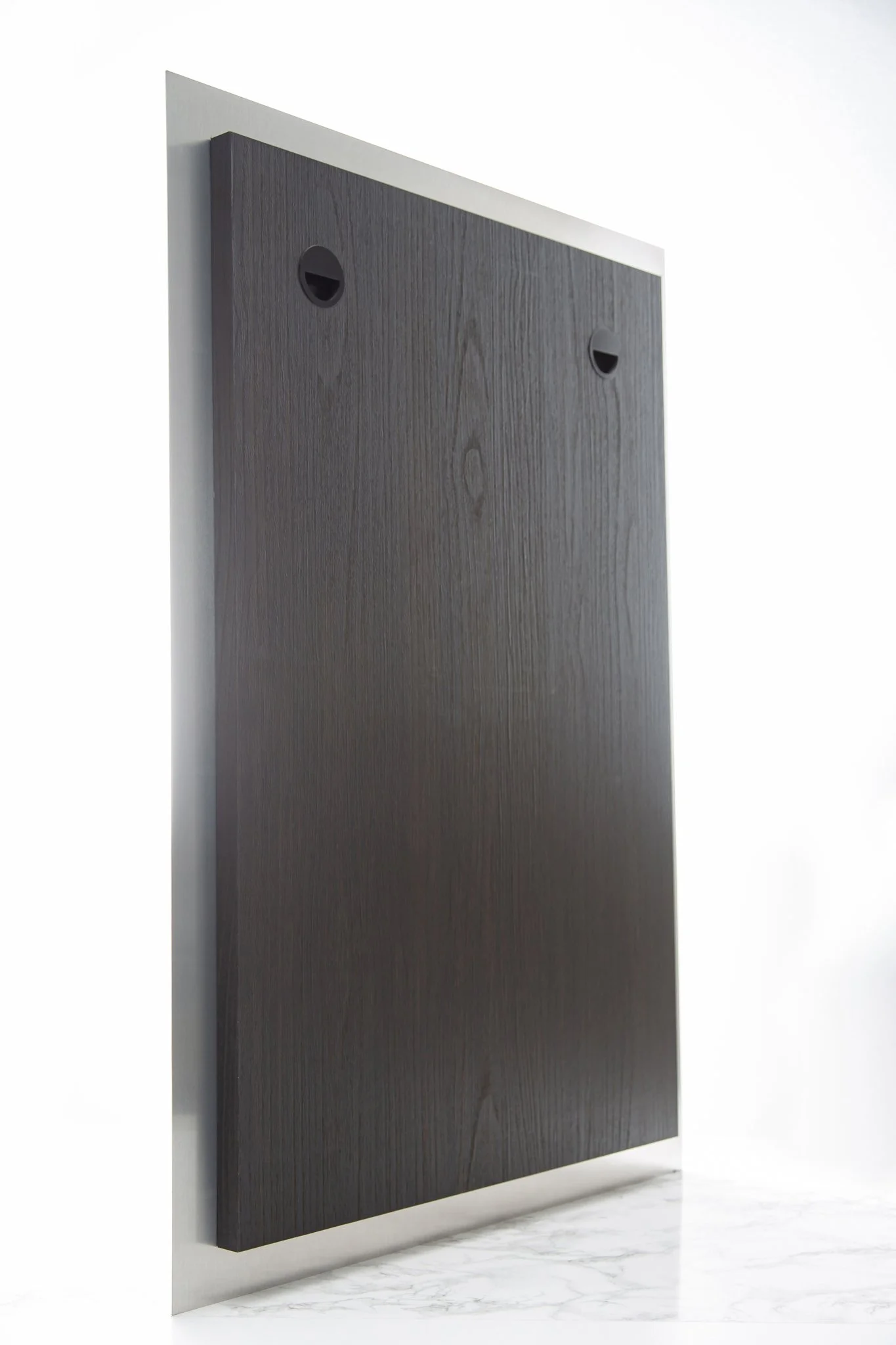 Close-up of a large, dark wooden panel mounted on a white wall, with two small circular black fixtures near the top.