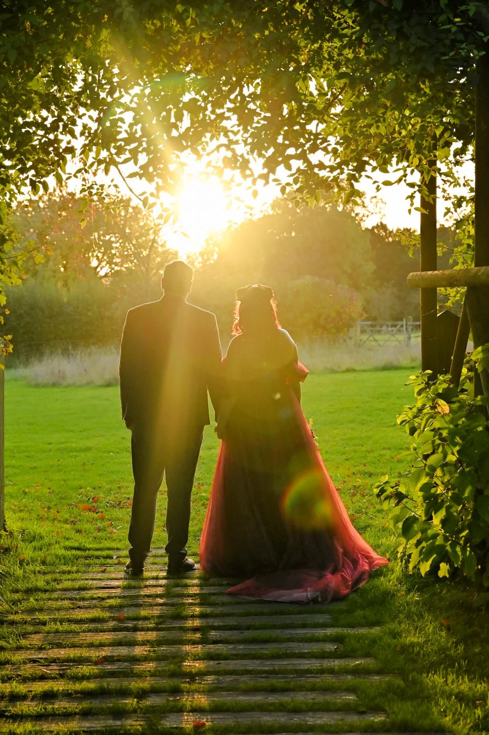 Bride in pink ballgown and groom silhouetted against a stunning golden sunset in Nottinghamshire countryside — romantic golden hour wedding photography by Tasha Boorman, Nottinghamshire wedding photographer