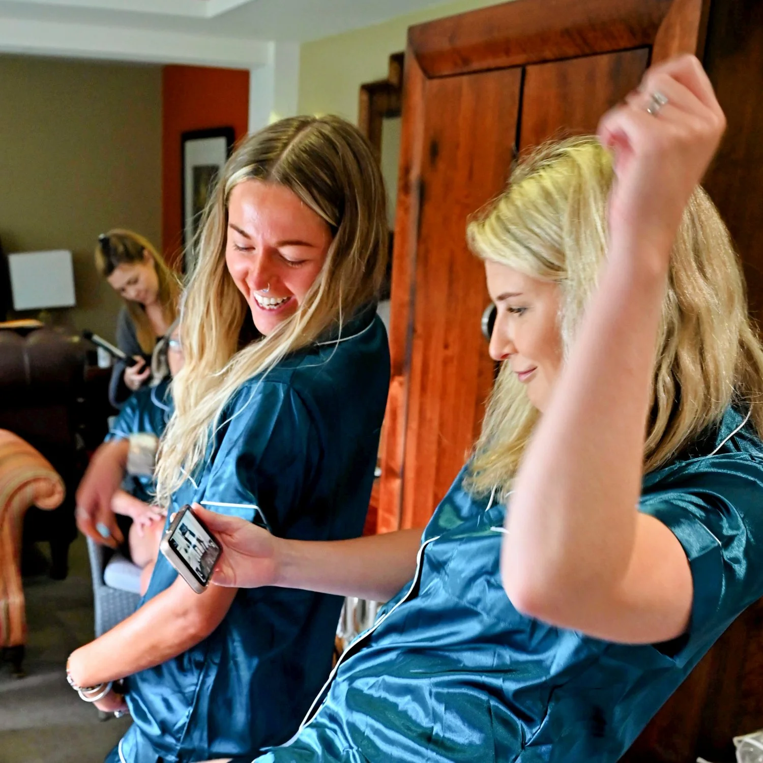 Bridesmaids in matching satin pyjamas dancing and laughing together during wedding morning preparations — candid getting ready photography by Tasha Boorman, Nottinghamshire wedding photographer