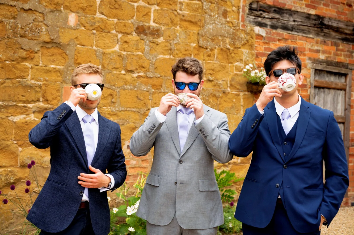 Groom and groomsmen looking cool in sunglasses drinking tea from china cups at The Courtyard Barns, Leicestershire — fun groomsmen portrait by Tasha Boorman, Leicestershire wedding photographer