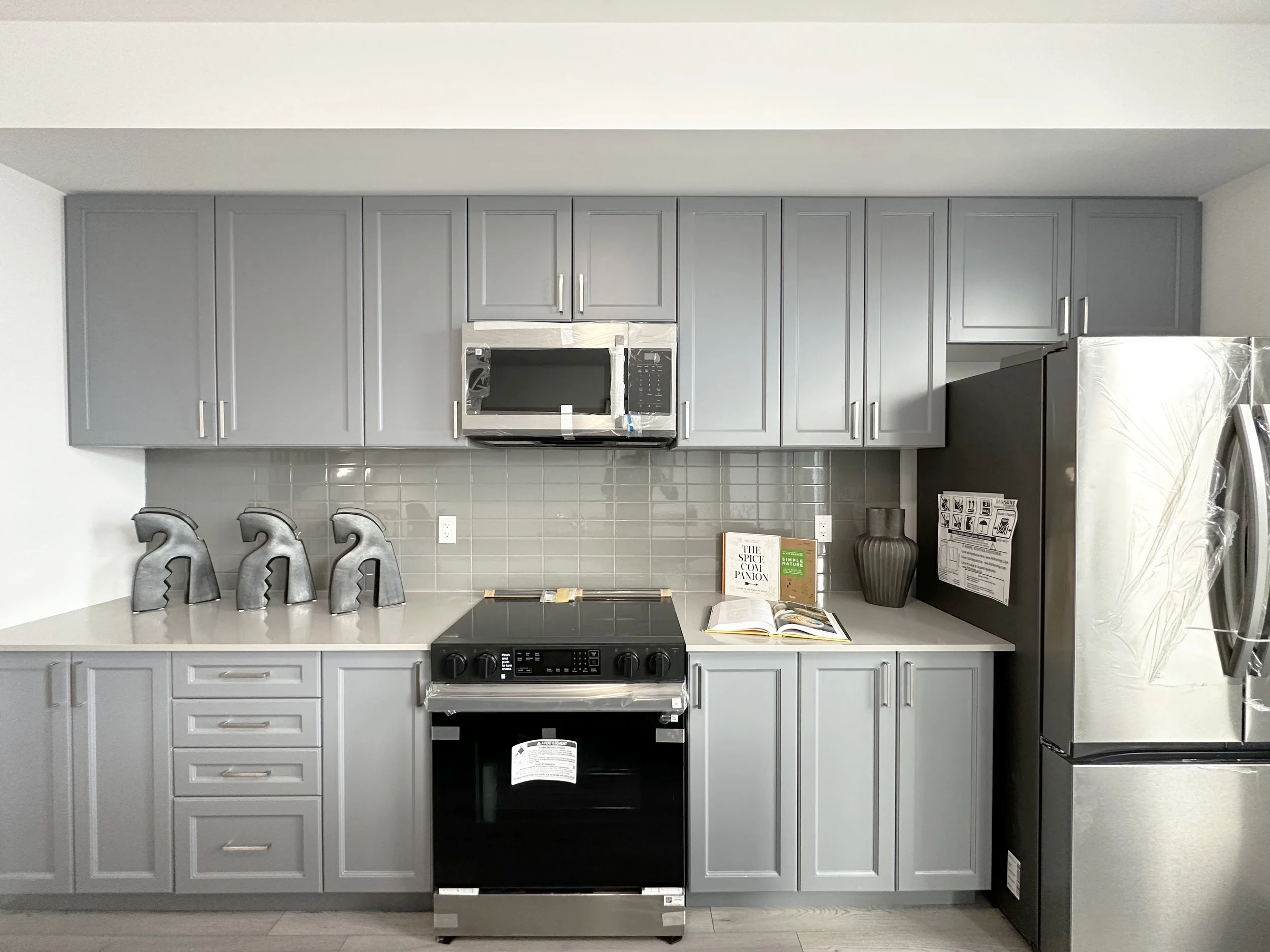 Kitchen with gray cabinets, a black stove, a microwave, and decorative letters on the counter.