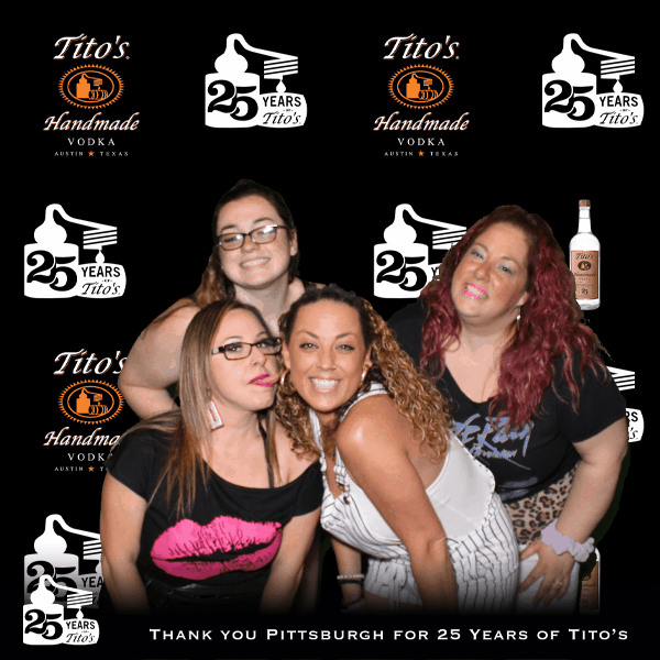 Four women pose in front of Tito’s Handmade Vodka 25th anniversary logos with the message “Thank You Pittsburgh for 25 Years of Tito’s.”