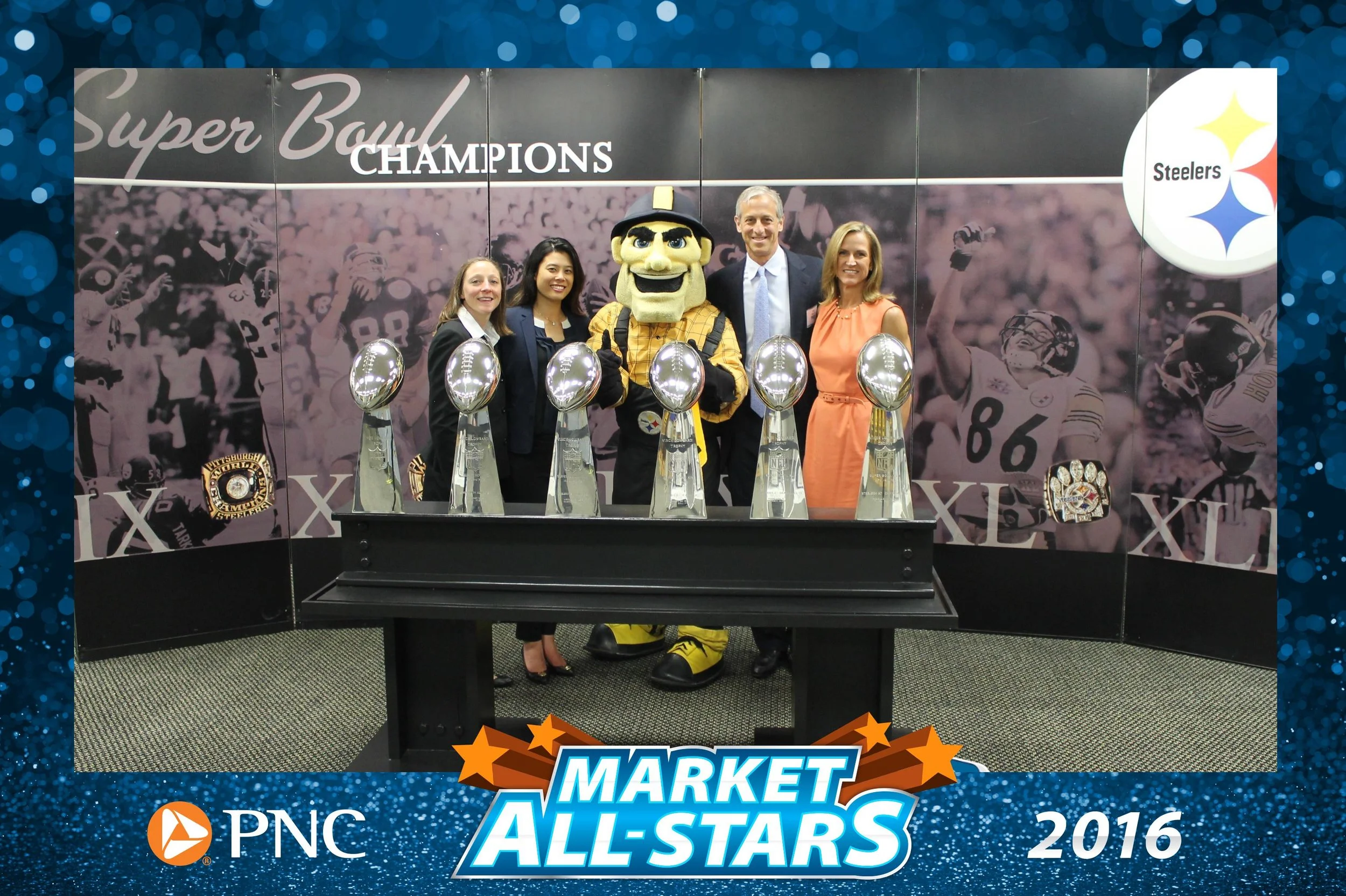 People and the Pittsburgh Steelers mascot pose with six Super Bowl trophies at a 2016 PNC Market All-Stars event.