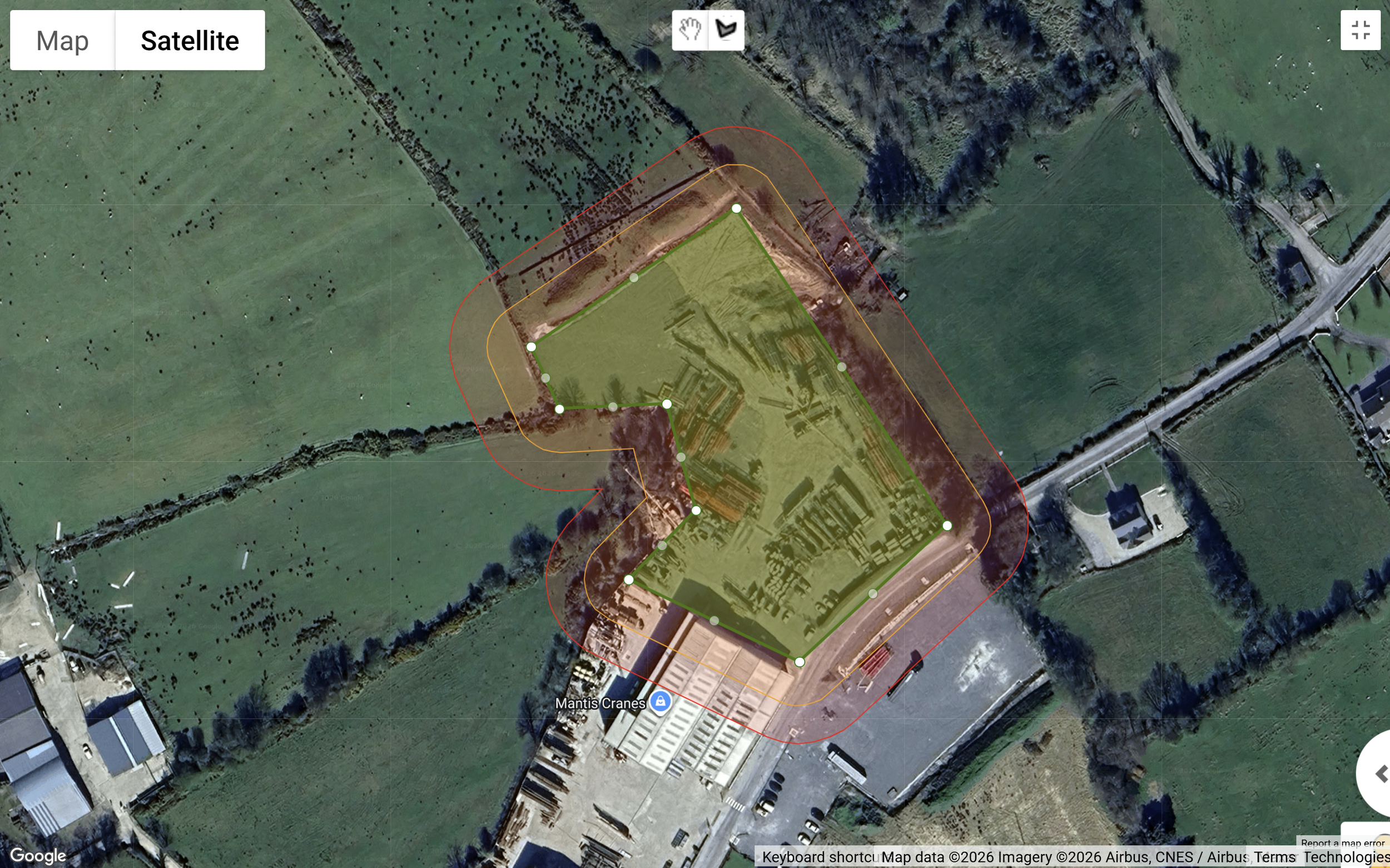 Satellite view of a large sports or event field with color-coded boundaries, surrounded by buildings, roads, and green open spaces.