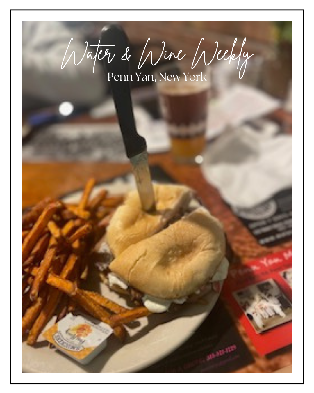 A plate with a loaf of bread, some fries, and a knife stuck in the bread on a table at a restaurant or cafe.