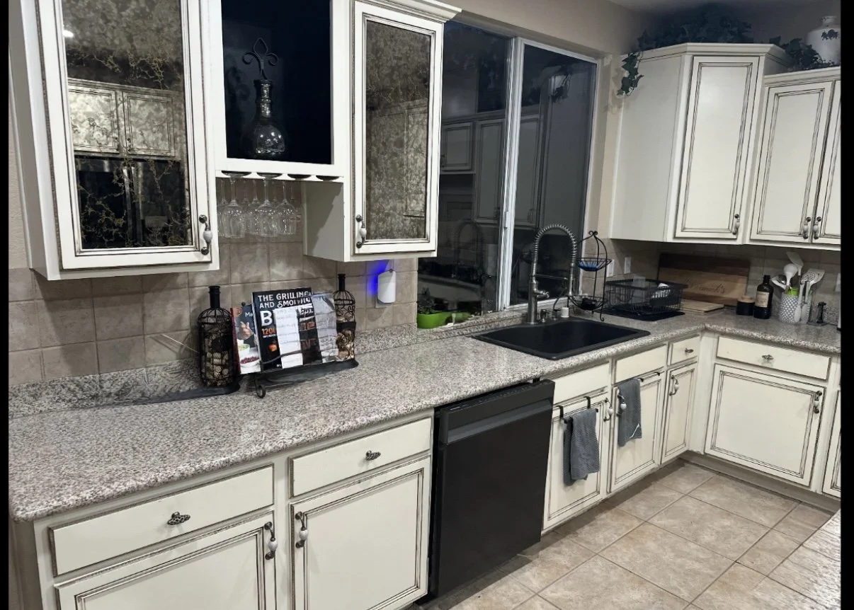 A new remodeled kitchen with white cabinets, granite countertops, and a black sink. Including custom glass-front upper cabinets.