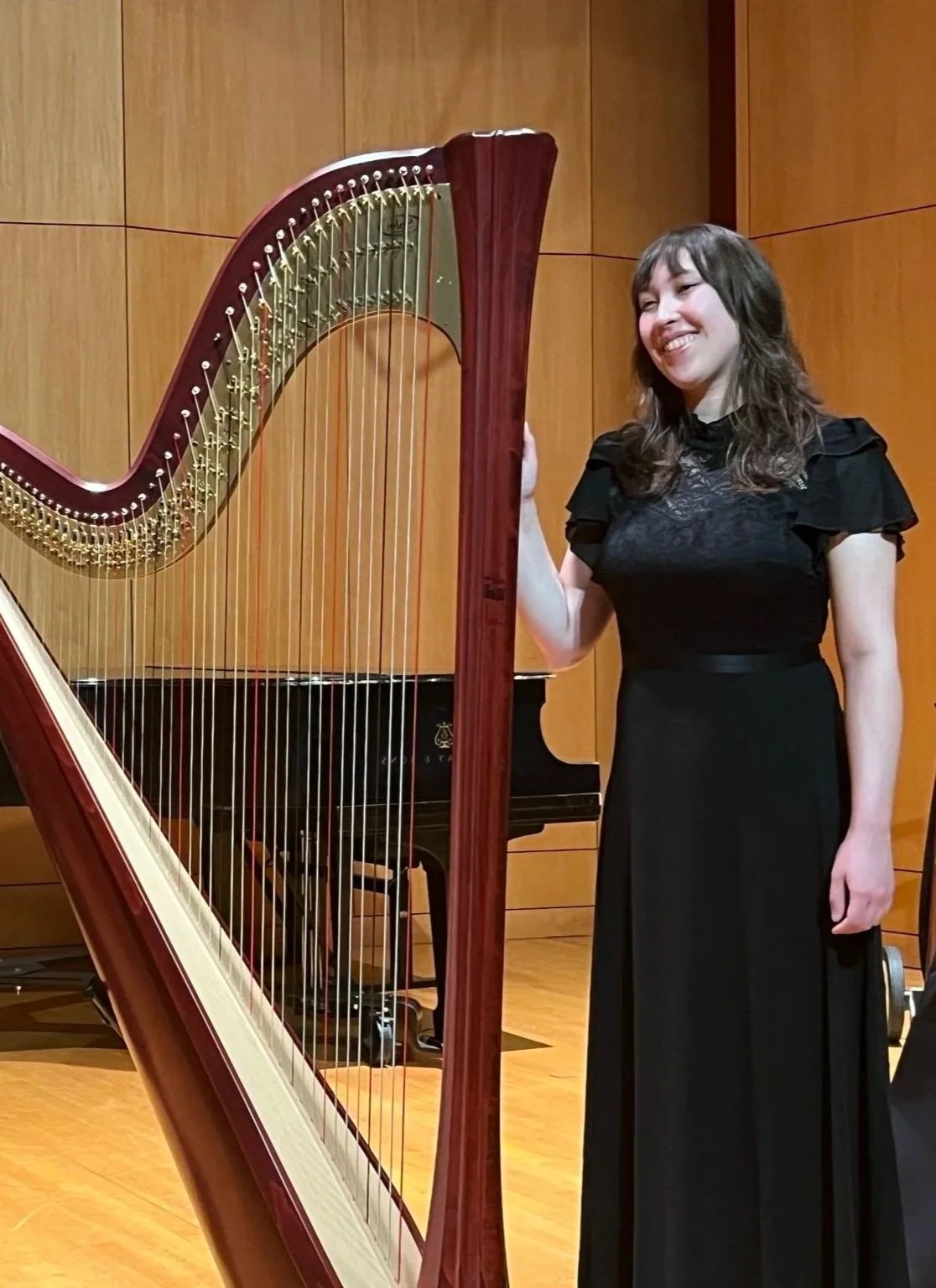 Hannah standing next to the harp after a recital