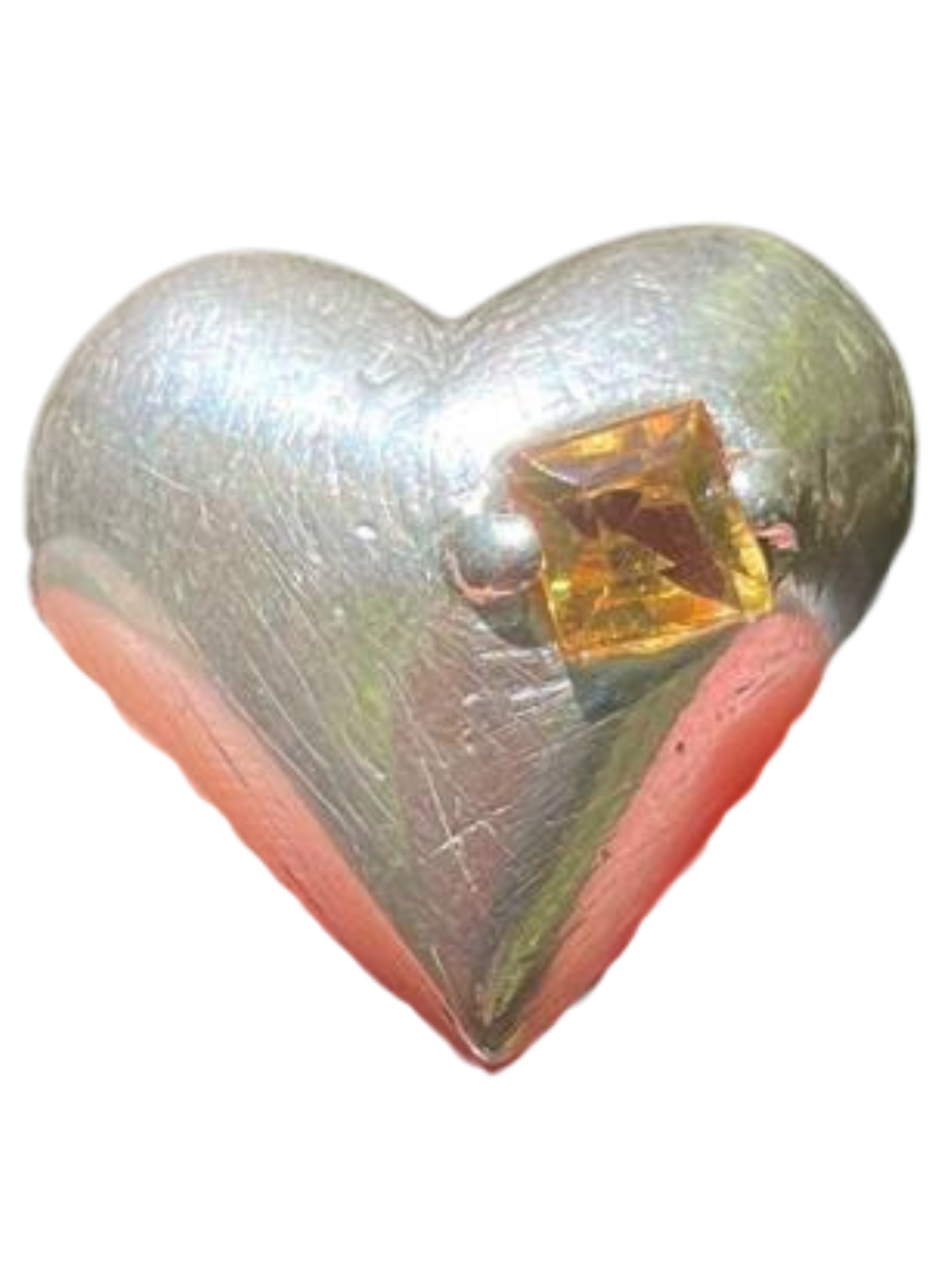 A shiny silver heart-shaped object with a small amber-colored gemstone in the center.