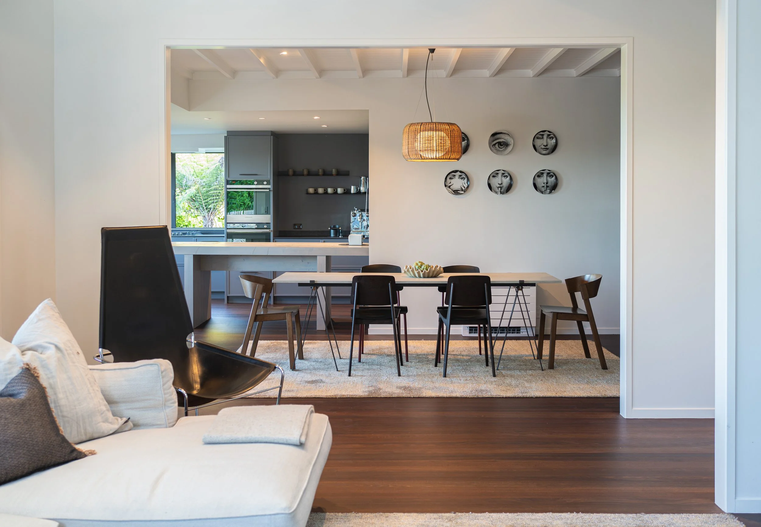 Modern open-plan dining and kitchen area with a table, chairs, and contemporary wall art.