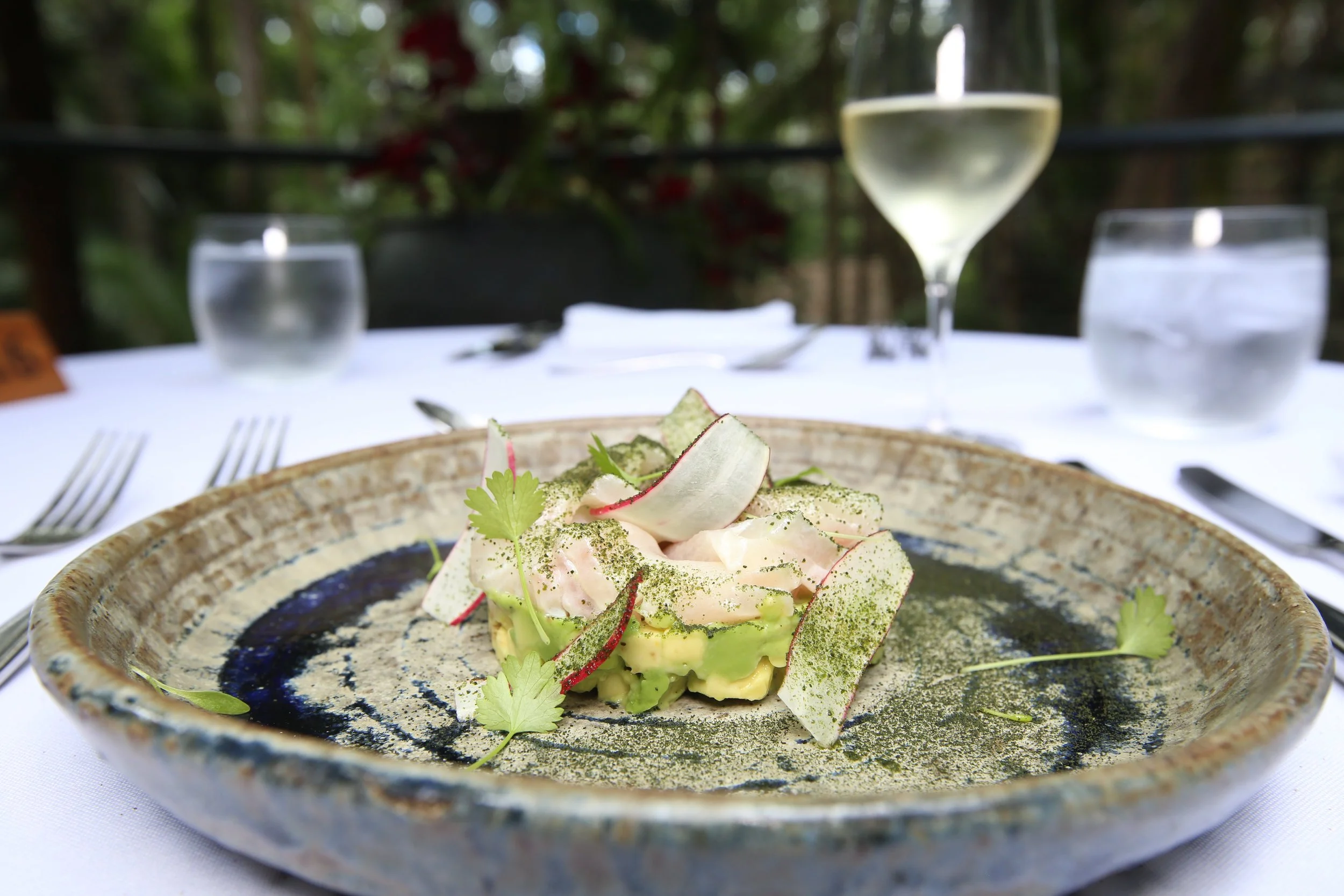 Cured kingfish with avocado and radish on a blue-glazed plate