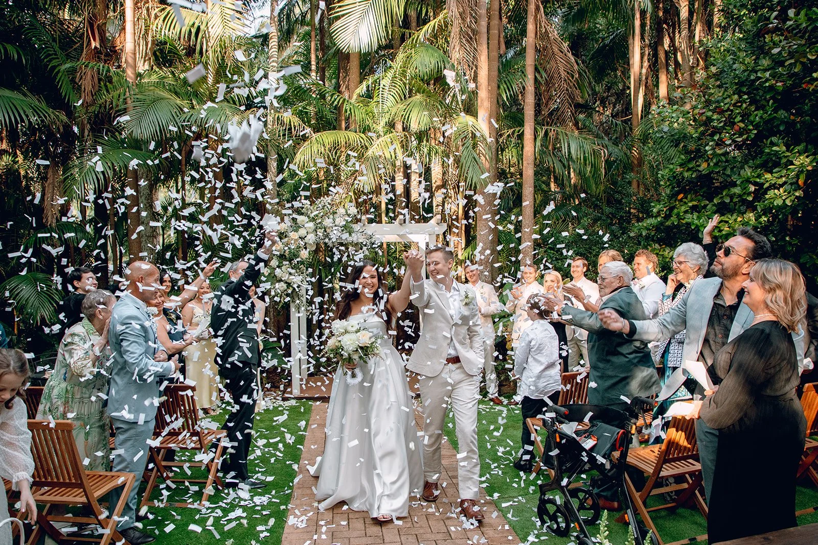 Newlyweds walking through confetti after their rainforest ceremony