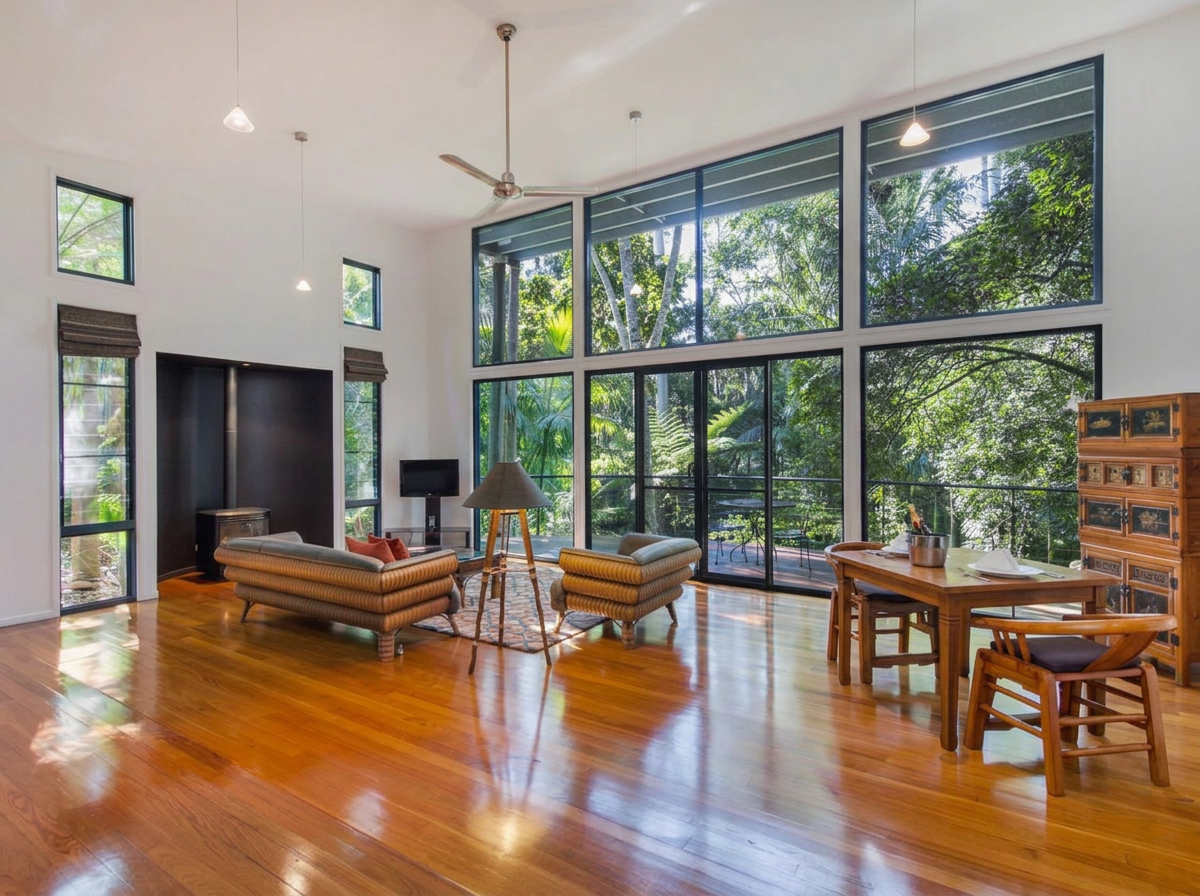 Villa living area with double-height glass walls looking into the rainforest canopy