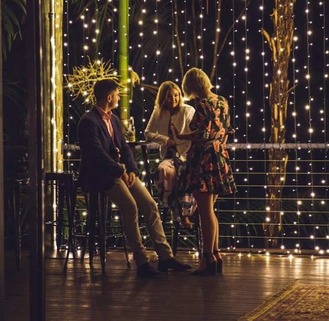 Guests talking at a cocktail event under fairy lights