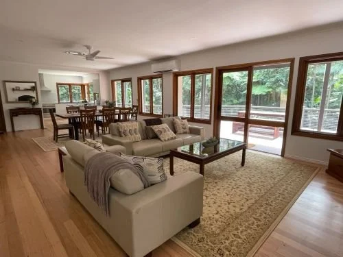 Open-plan living and dining area with timber floors and windows onto the garden