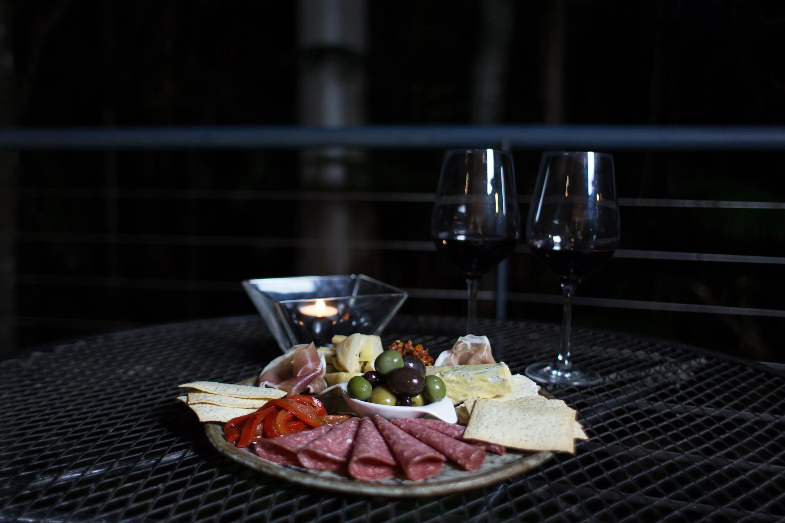 Antipasto platter with olives, cured meats and cheese, served by candlelight