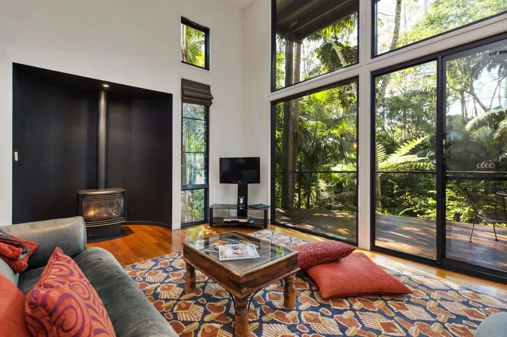 Villa living room with five-metre glass walls opening to the rainforest and deck