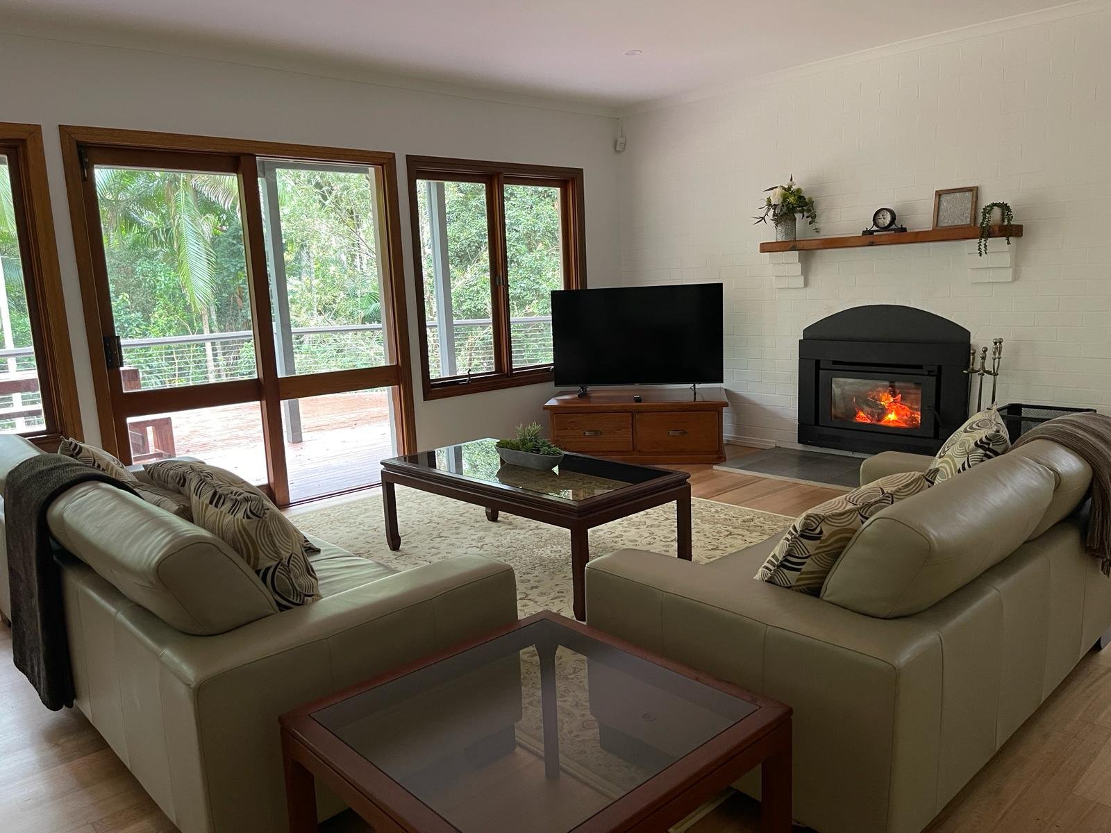 Second lounge area with a lit log fireplace and rainforest views