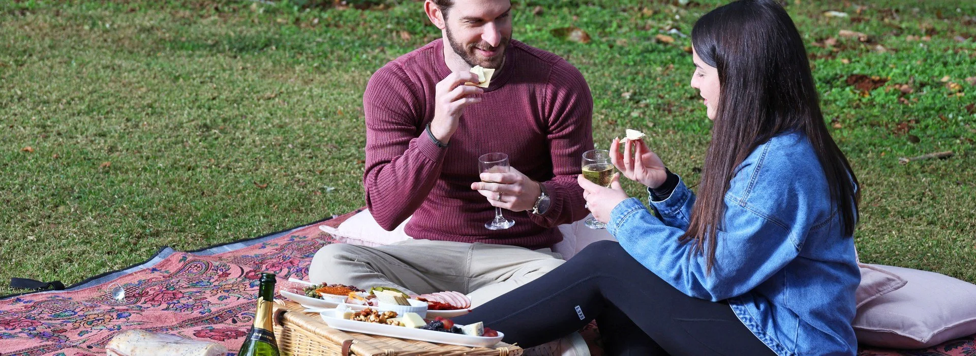 Couple sharing a cheese platter and wine on the lawn