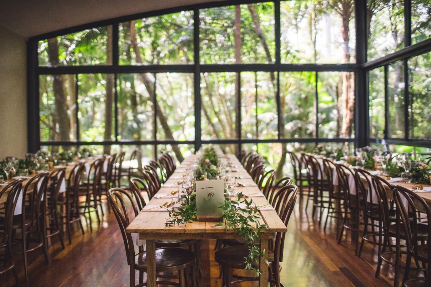Long reception table with greenery runners in the glass-walled Lodge